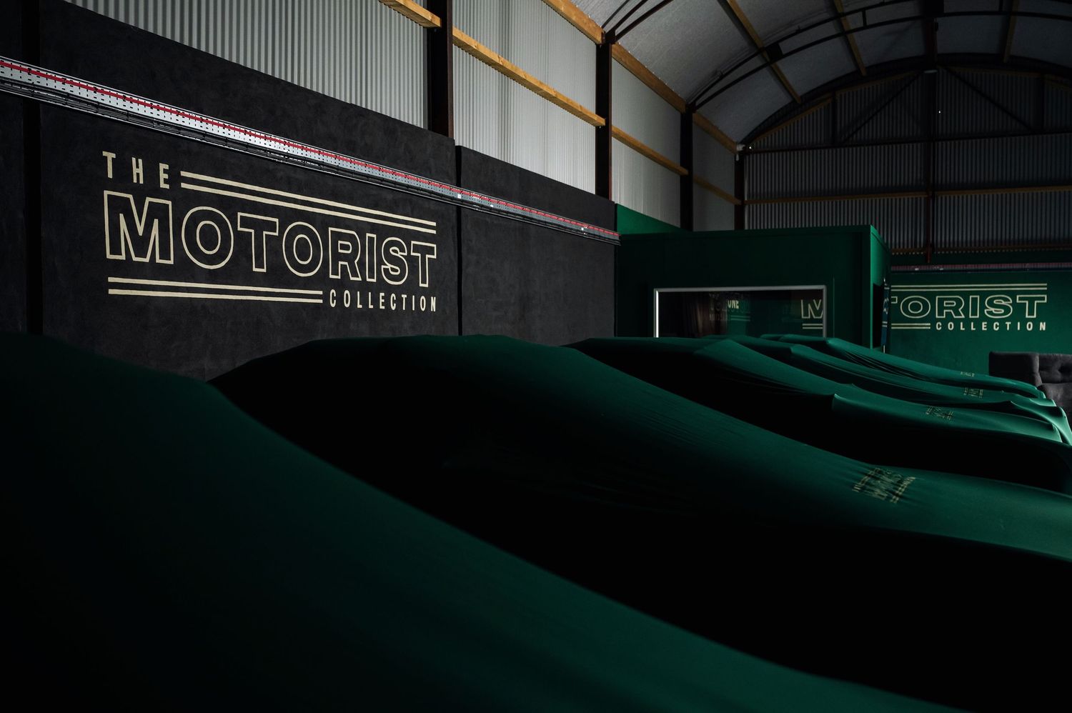 Interior of The Motorist Collection storage facility with rows of car covers in a large dark warehouse space. Motorist Collection