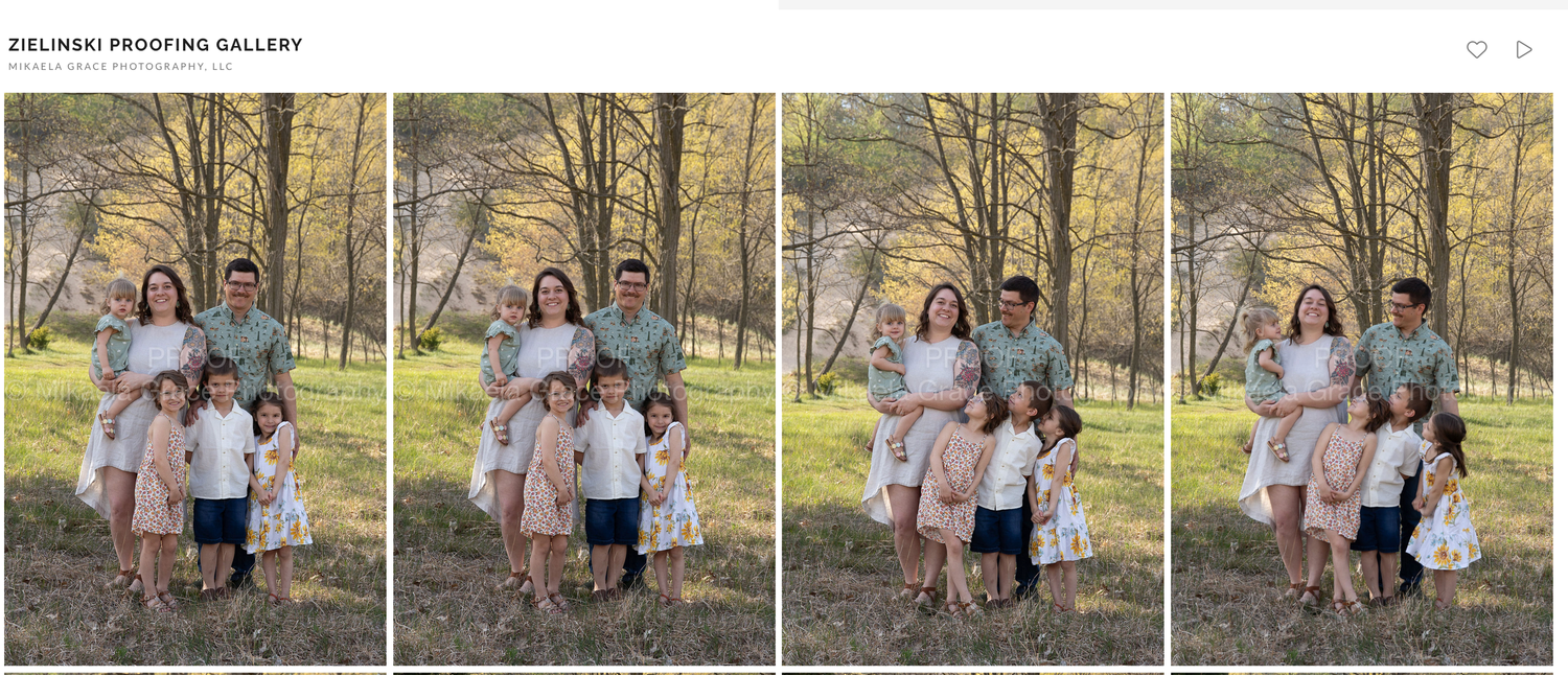 Family portrait with parents and three young children posing outdoors among autumn trees in coordinated pastel outfits.