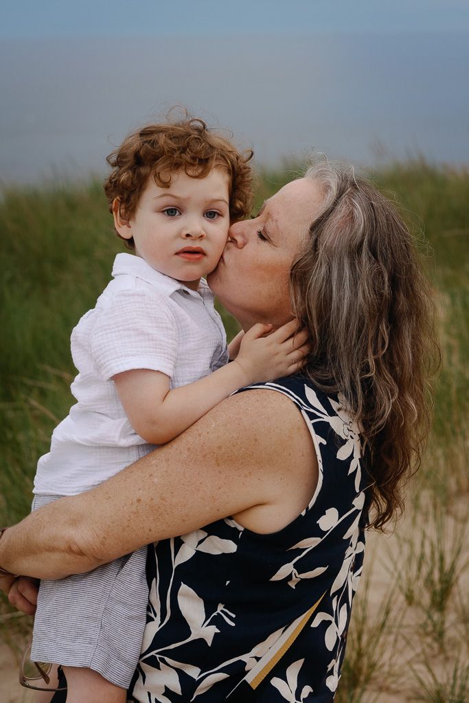 A tender moment shared between parent and child on a grassy hillside at sunset.