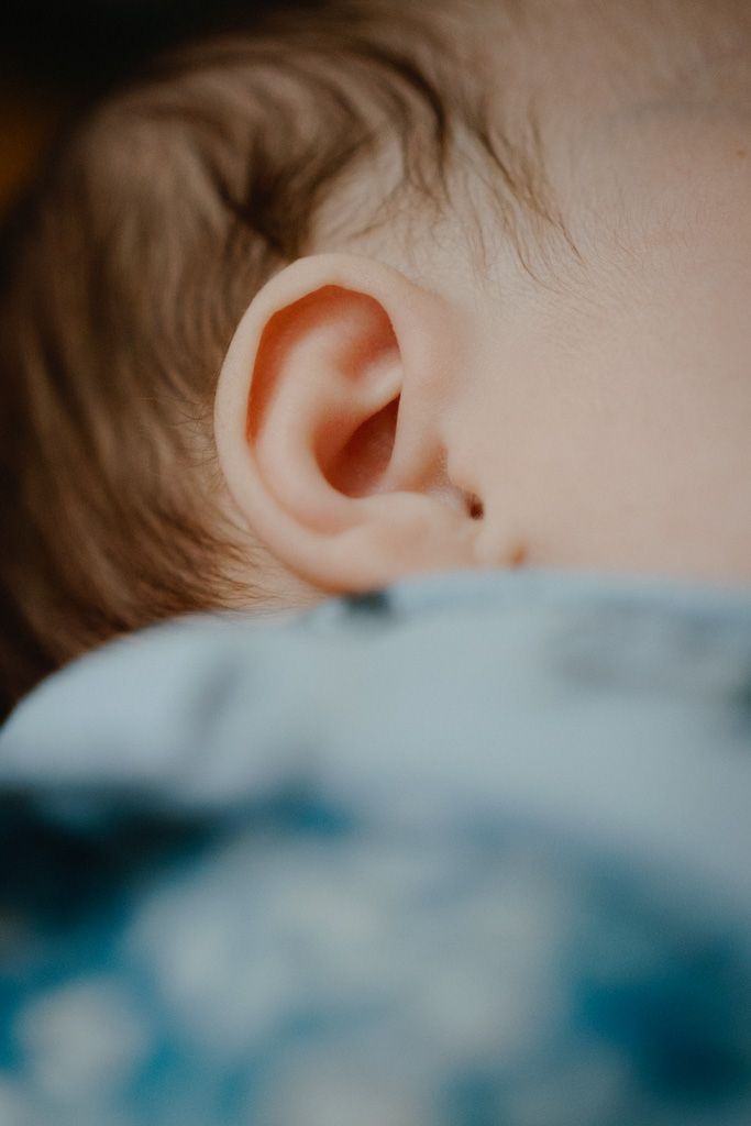 Close-up macro shot of a baby's ear against blue fabric.