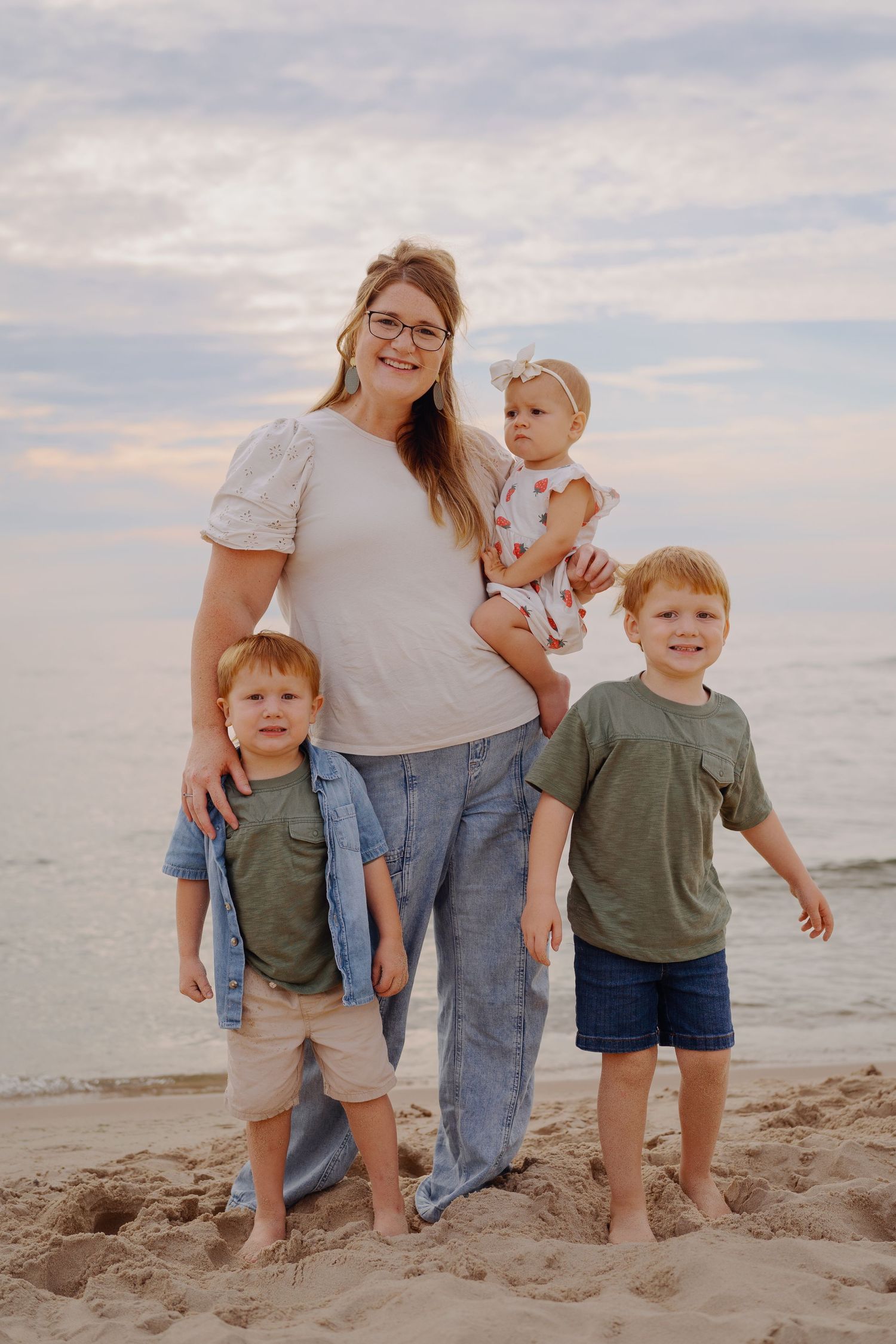 Family group posing together on sandy beach at sunset.