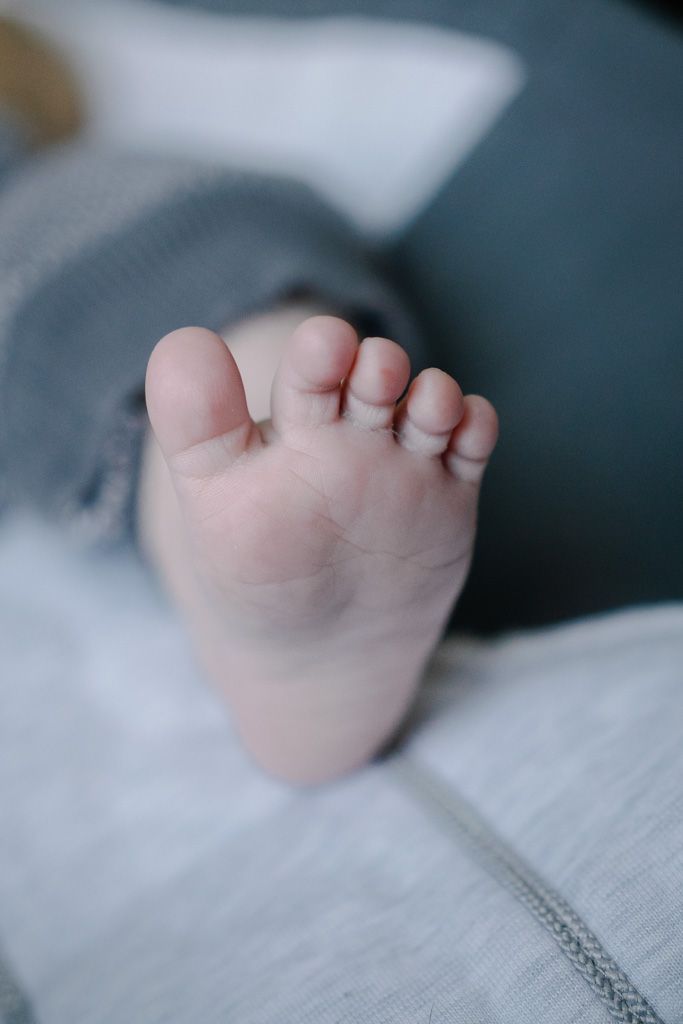 Close-up detail of tiny baby toes against white fabric.