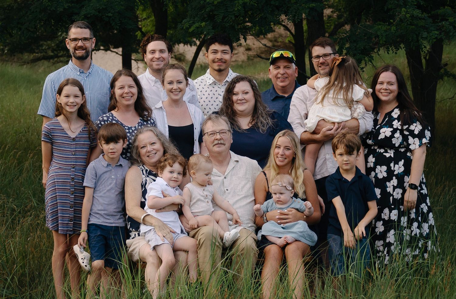 Extended family portrait session in a lush outdoor field during golden hour.