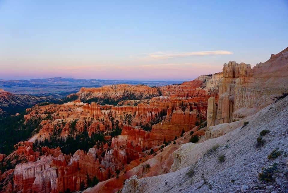 Panoramic view of Bryce Canyon's red rock formations and hoodoos at sunset.