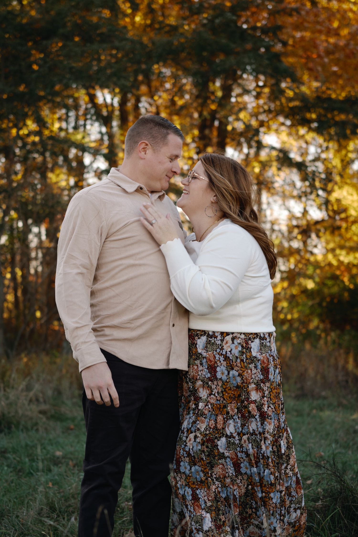 Romantic couple portraits in coordinated cream outfits against fall foliage.