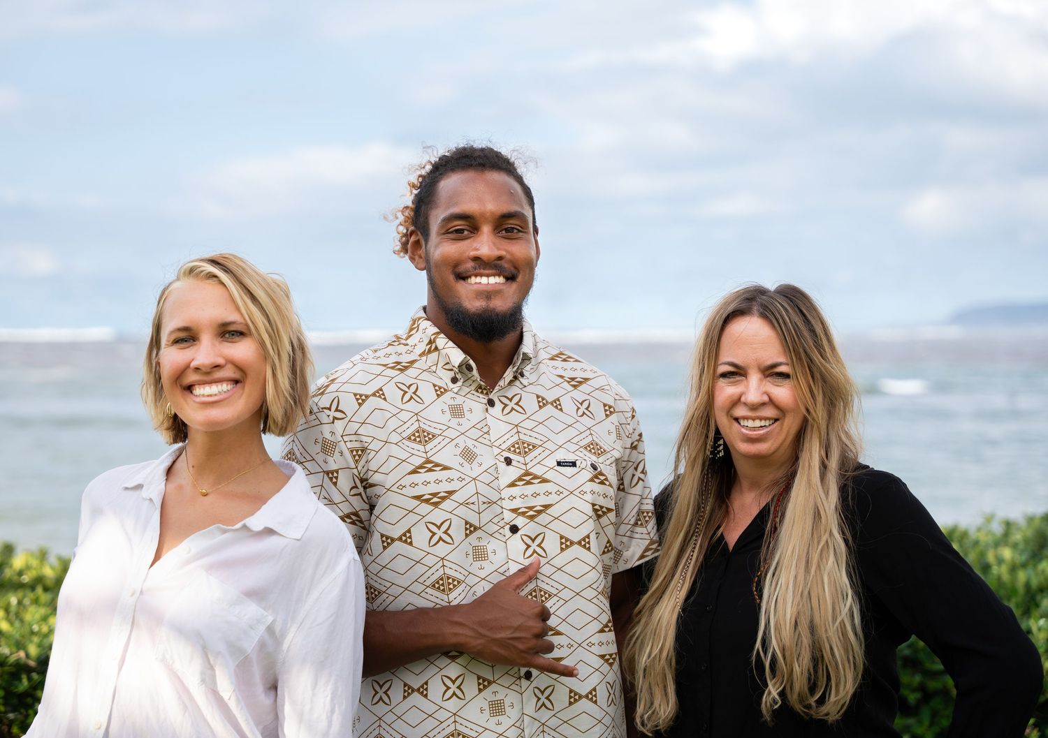 Three person portrait standing in front of the sea.