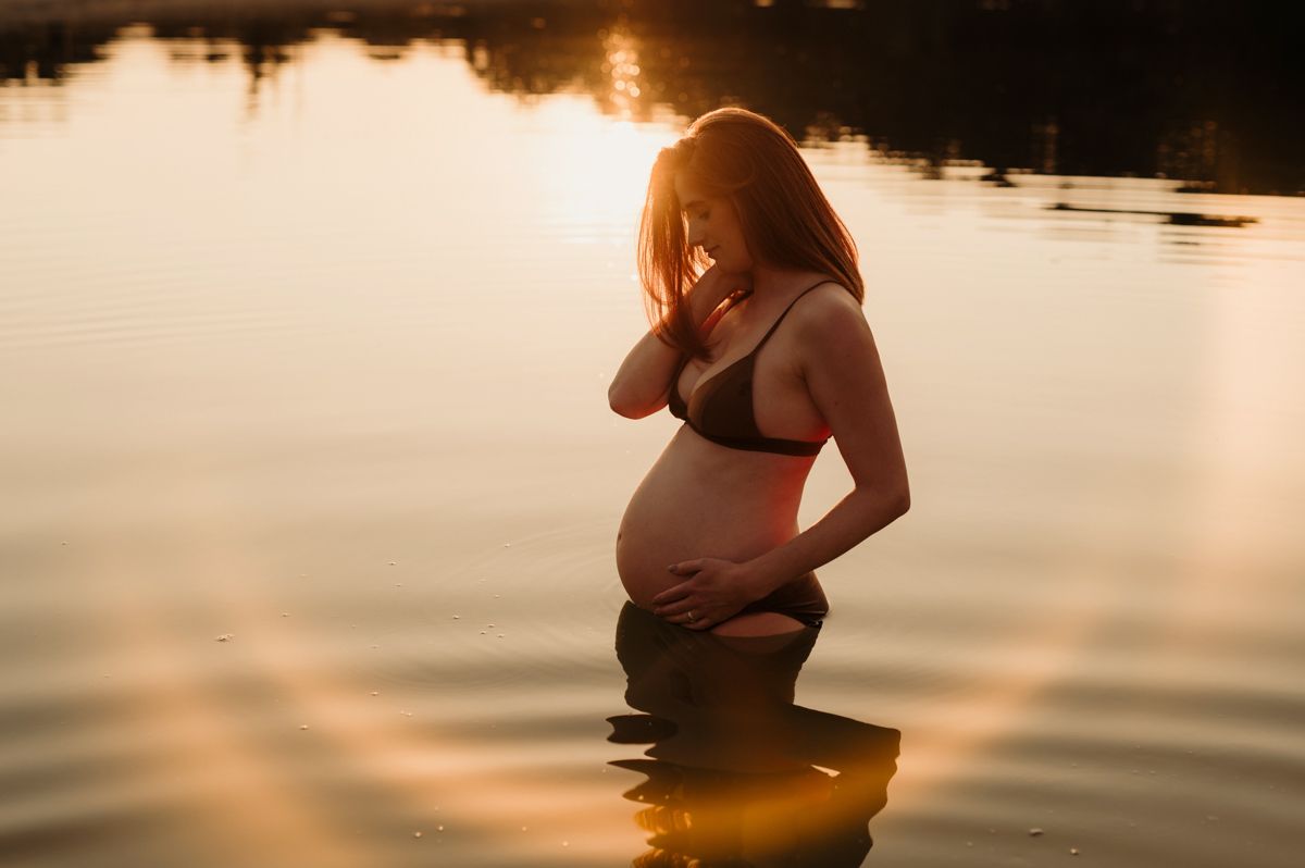 Zwangere vrouw tijdens een golden hour zwangerschapsshoot aan het water