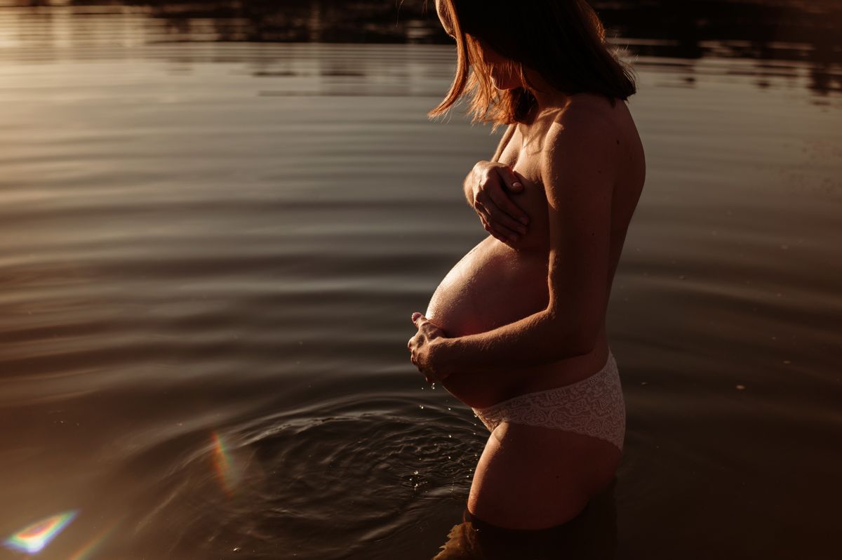 Zwangere vrouw tijdens een golden hour zwangerschapsshoot aan het water