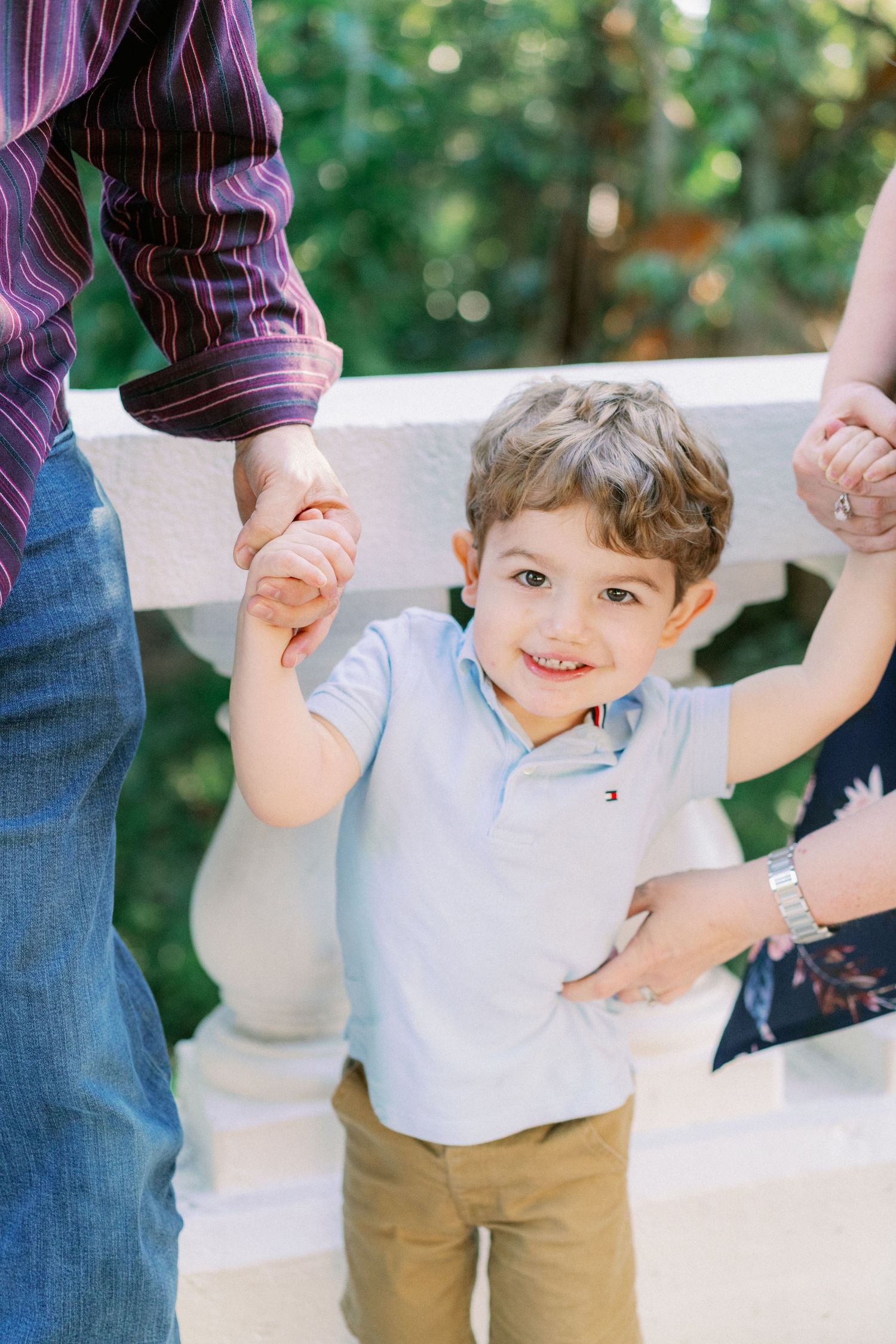 A sequence of photos showing a child swinging between adults' hands on a sunny outdoor patio.