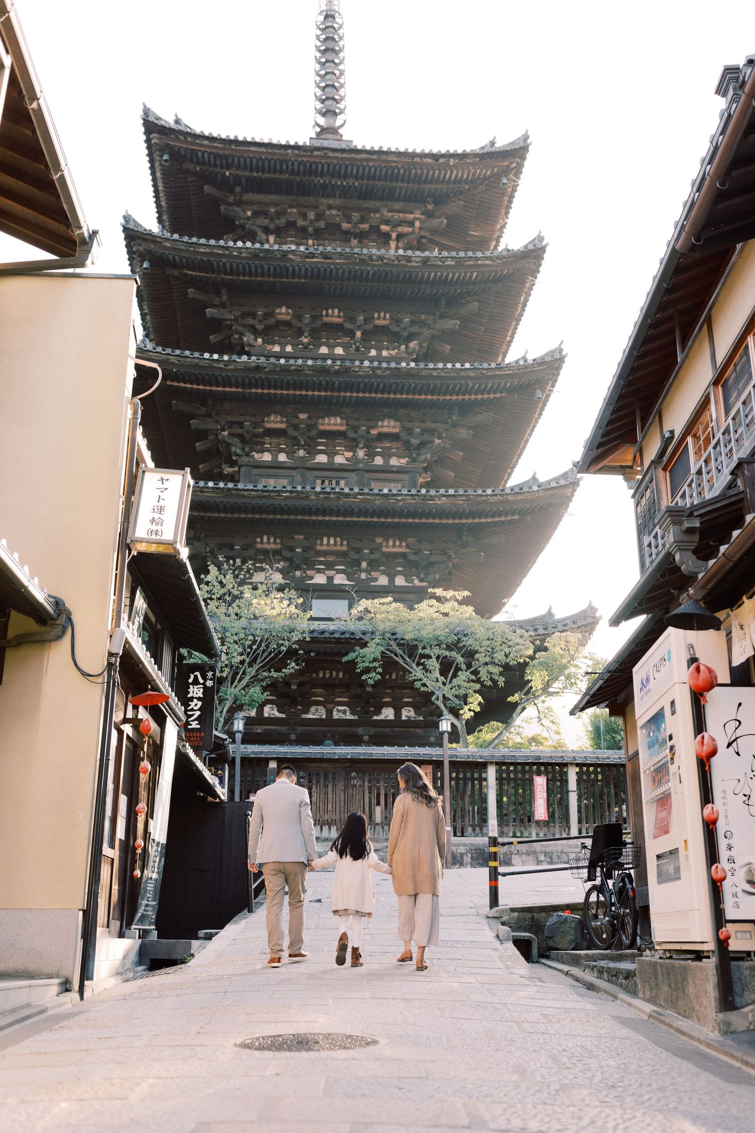 Traditional Japanese pagoda temple with visitors walking along covered pathway in Kyoto.