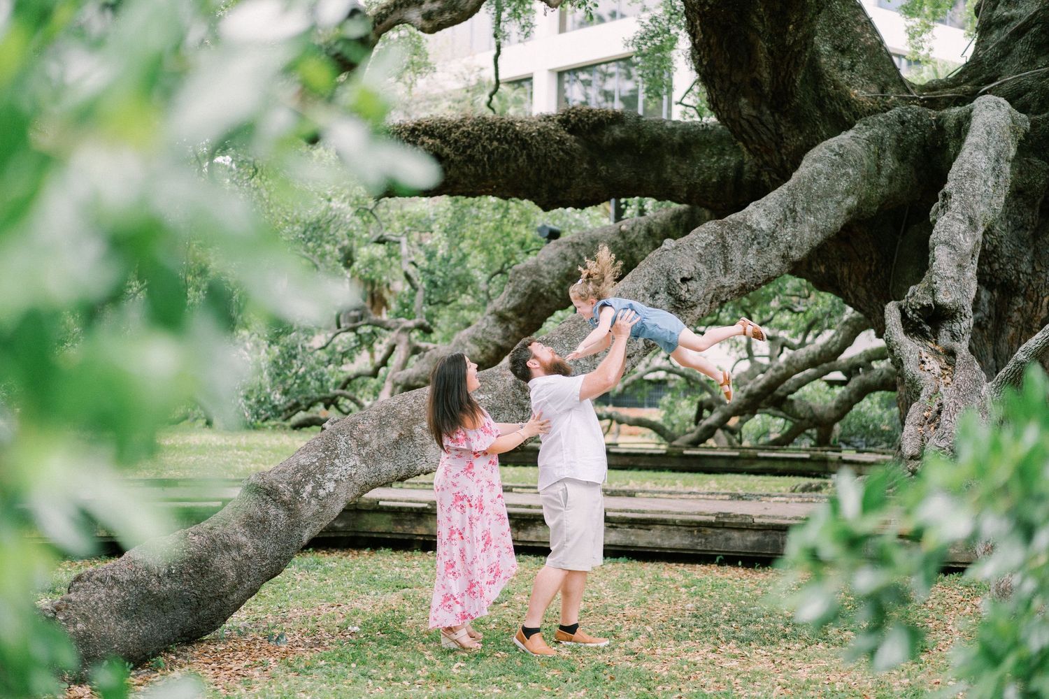 Couple dancing under sprawling tree branches in a park setting.