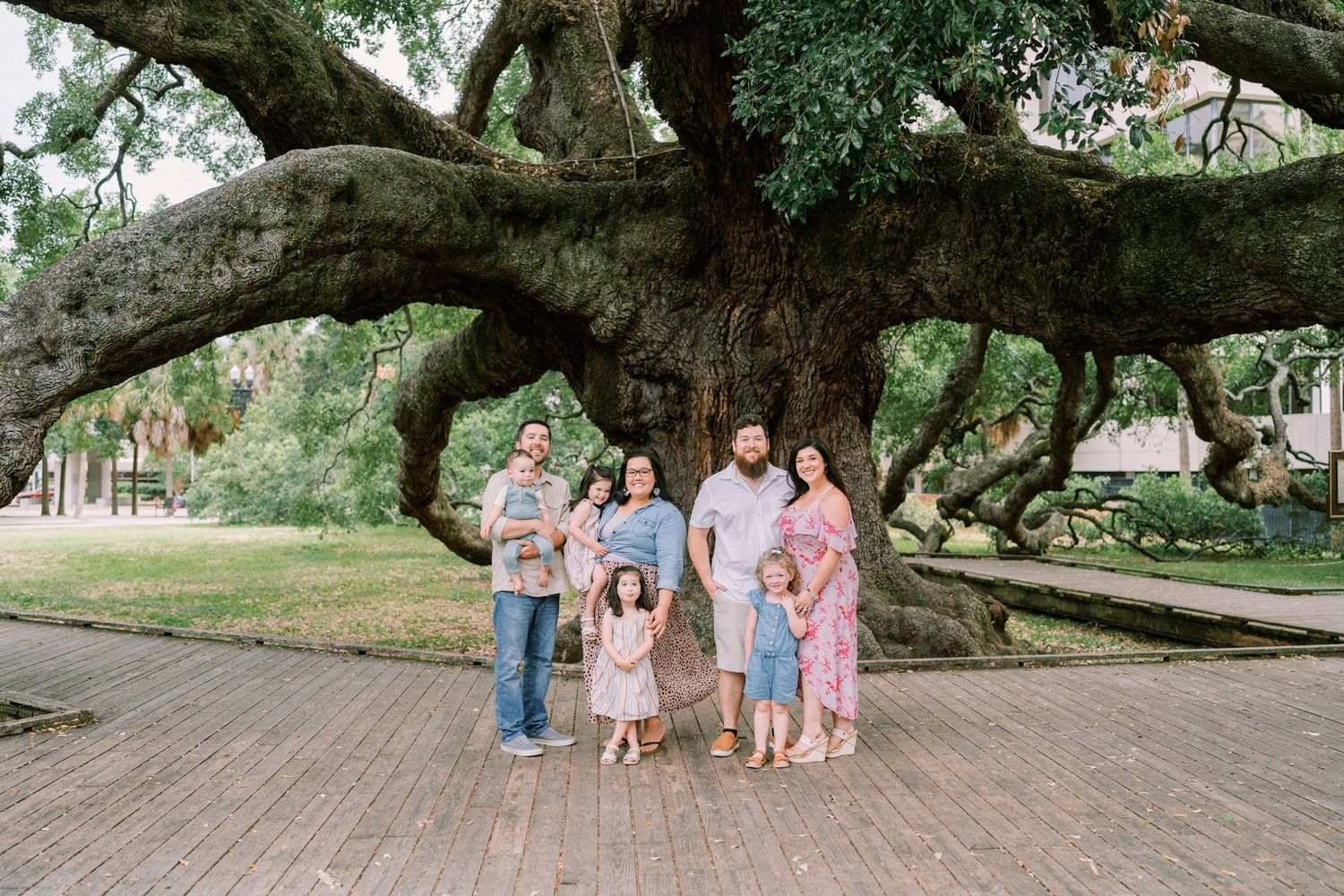 Group photo under massive oak tree branches in a park setting.