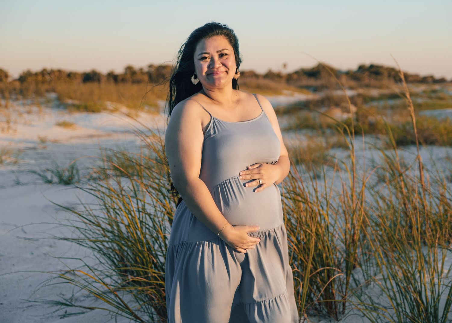 Maternity photo session at sunset with beach grass in the foreground.
