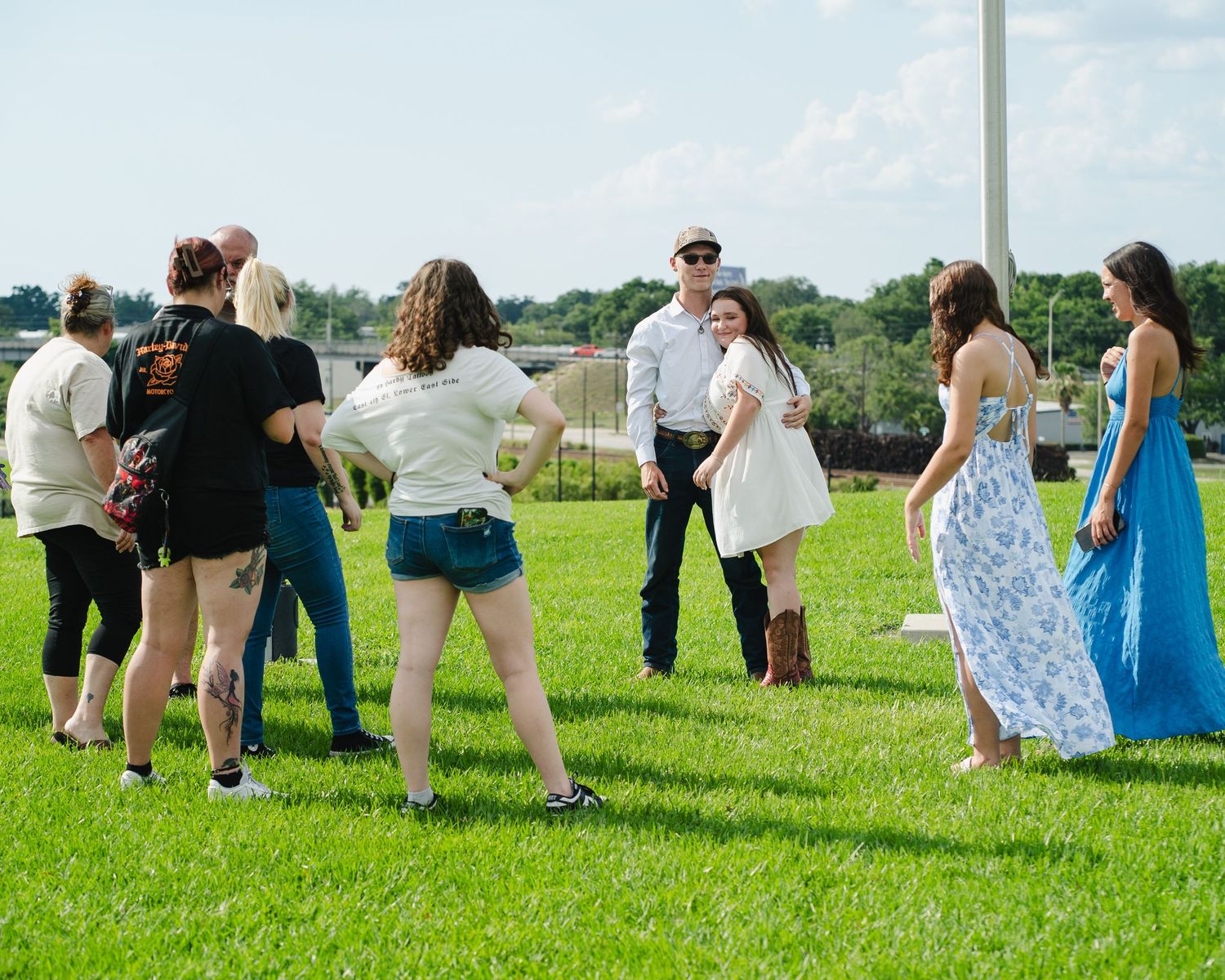 Group gathered outdoors on grassy field having animated conversation.