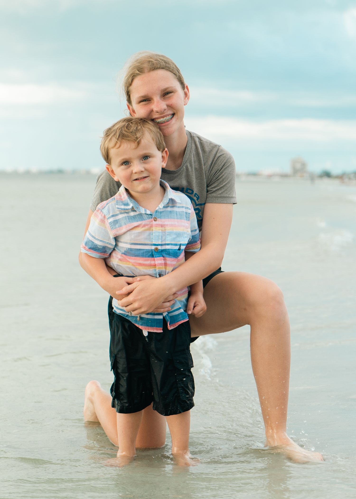 Playful beach scene with parent and child splashing in shallow water.