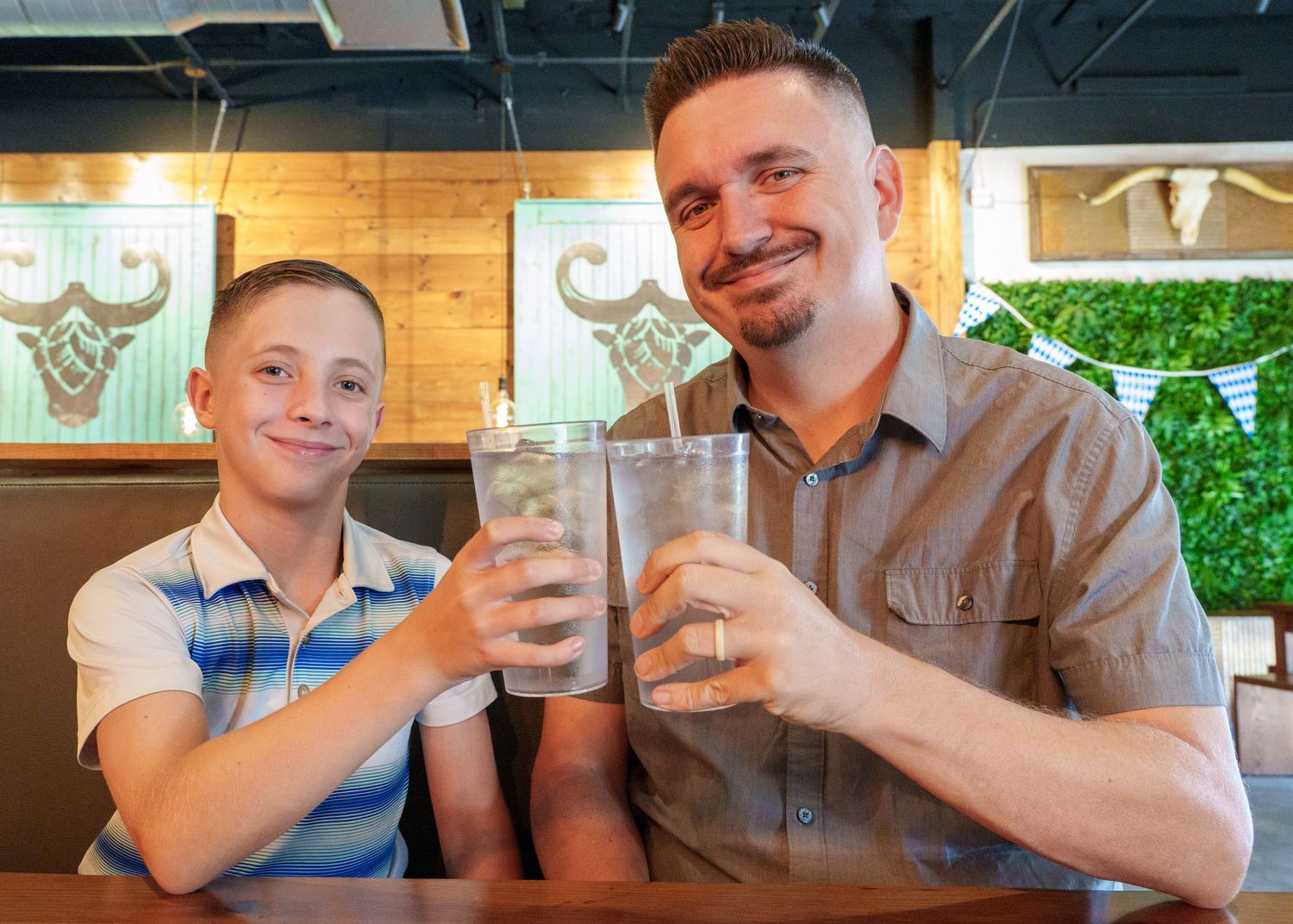 Two people clink glasses together at casual restaurant.