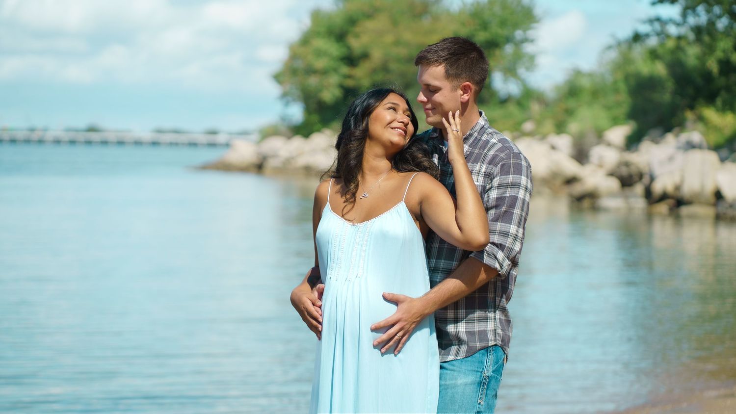 Romantic couple photoshoot by waterfront on sunny summer day.