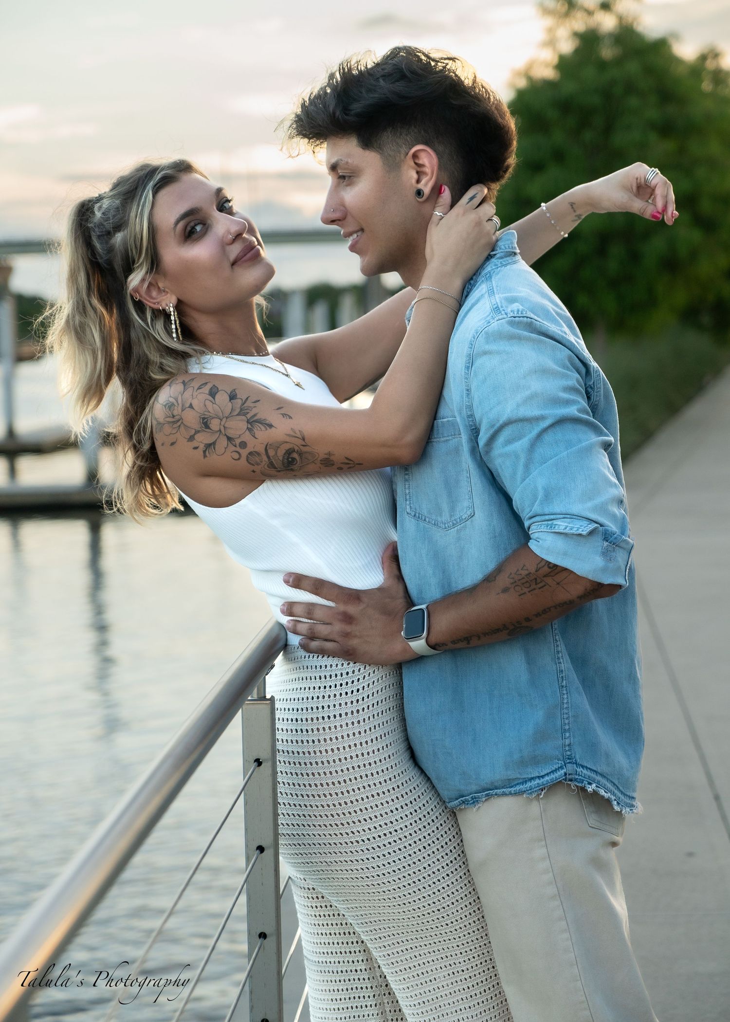 Romantic couple embracing on waterfront boardwalk at sunset.