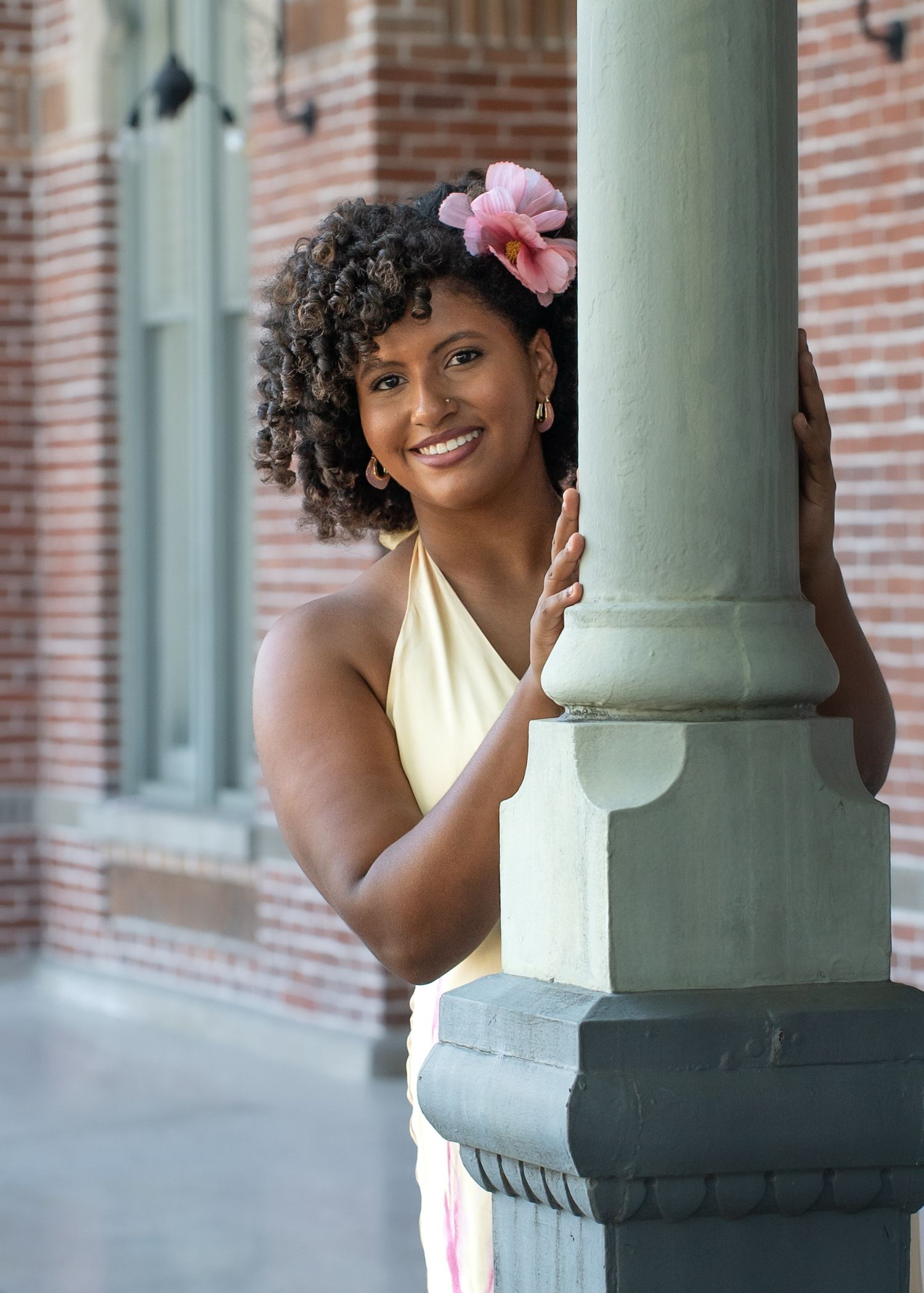 Playful poses around a decorative green column on a brick building's porch.