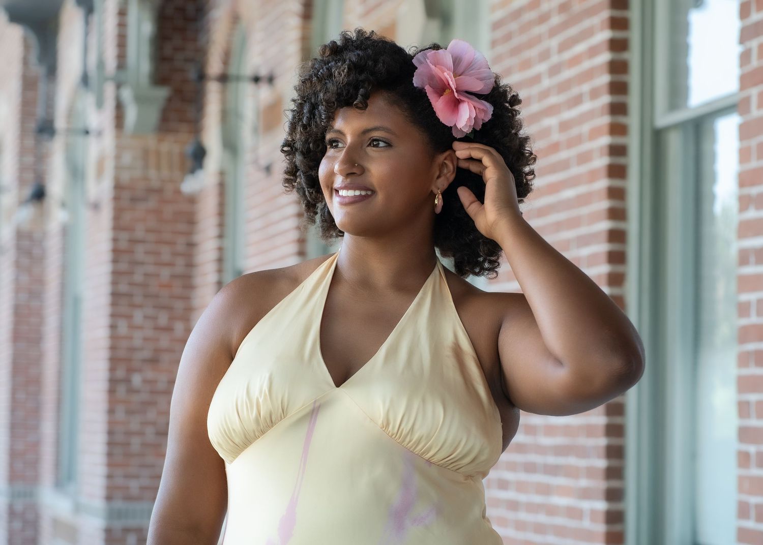 Elegant portrait session in a brick-columned walkway with natural lighting.