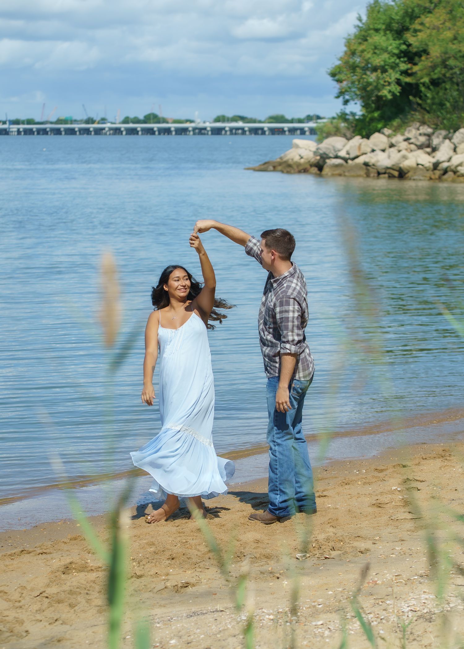 Couple dancing together on a sandy beach near the water.