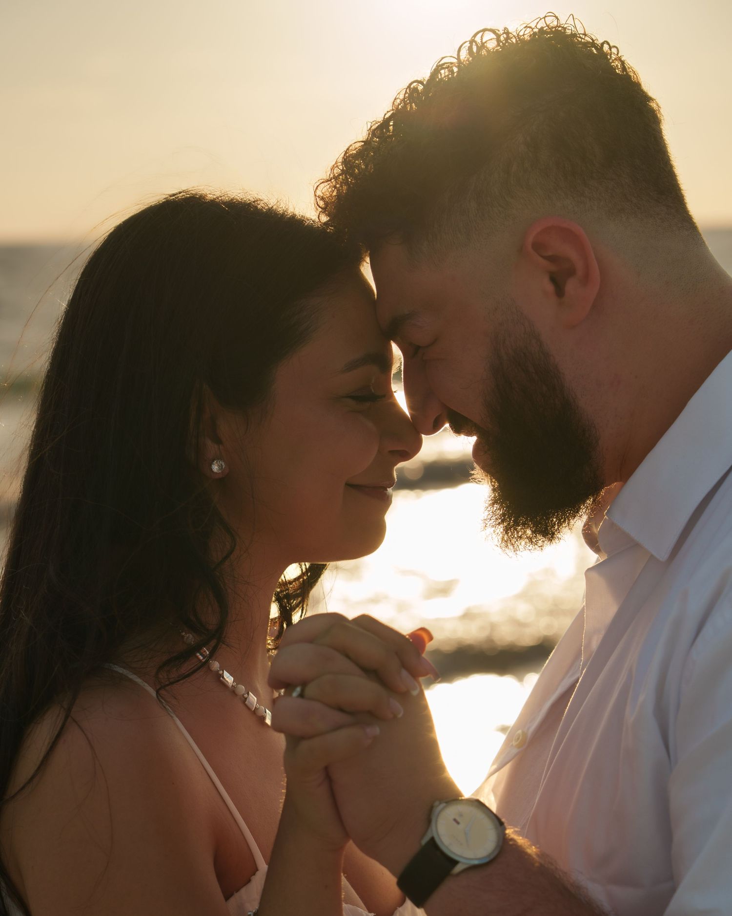 A tender moment between a couple during a sunset beach engagement session.