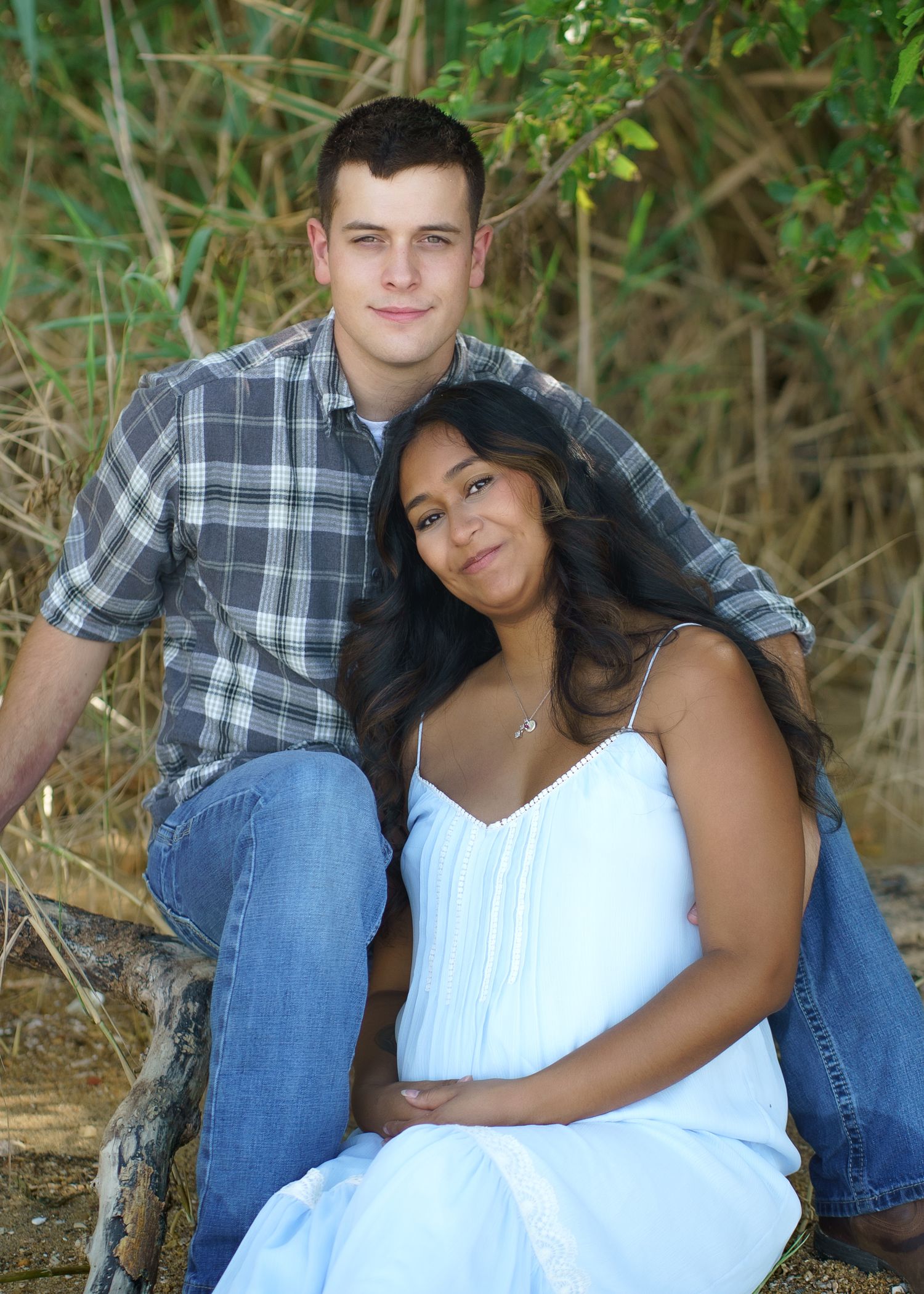 Couple posing together outdoors against natural foliage background.