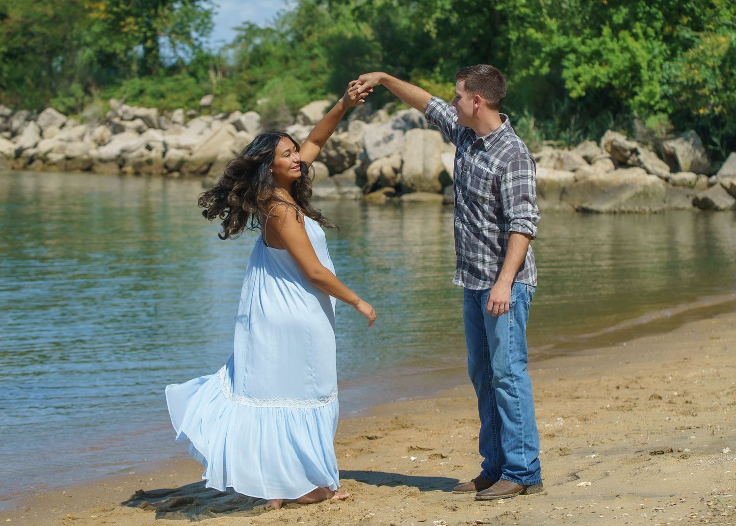 A romantic photoshoot by the water's edge with scenic natural backdrop.