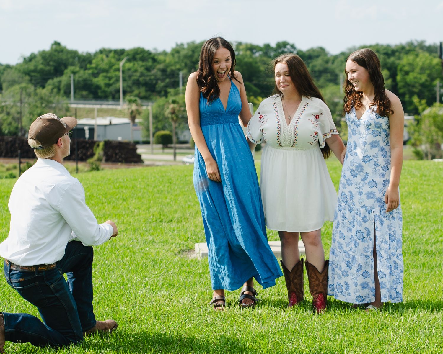 People gathered on a grassy field wearing summer dresses and casual attire.