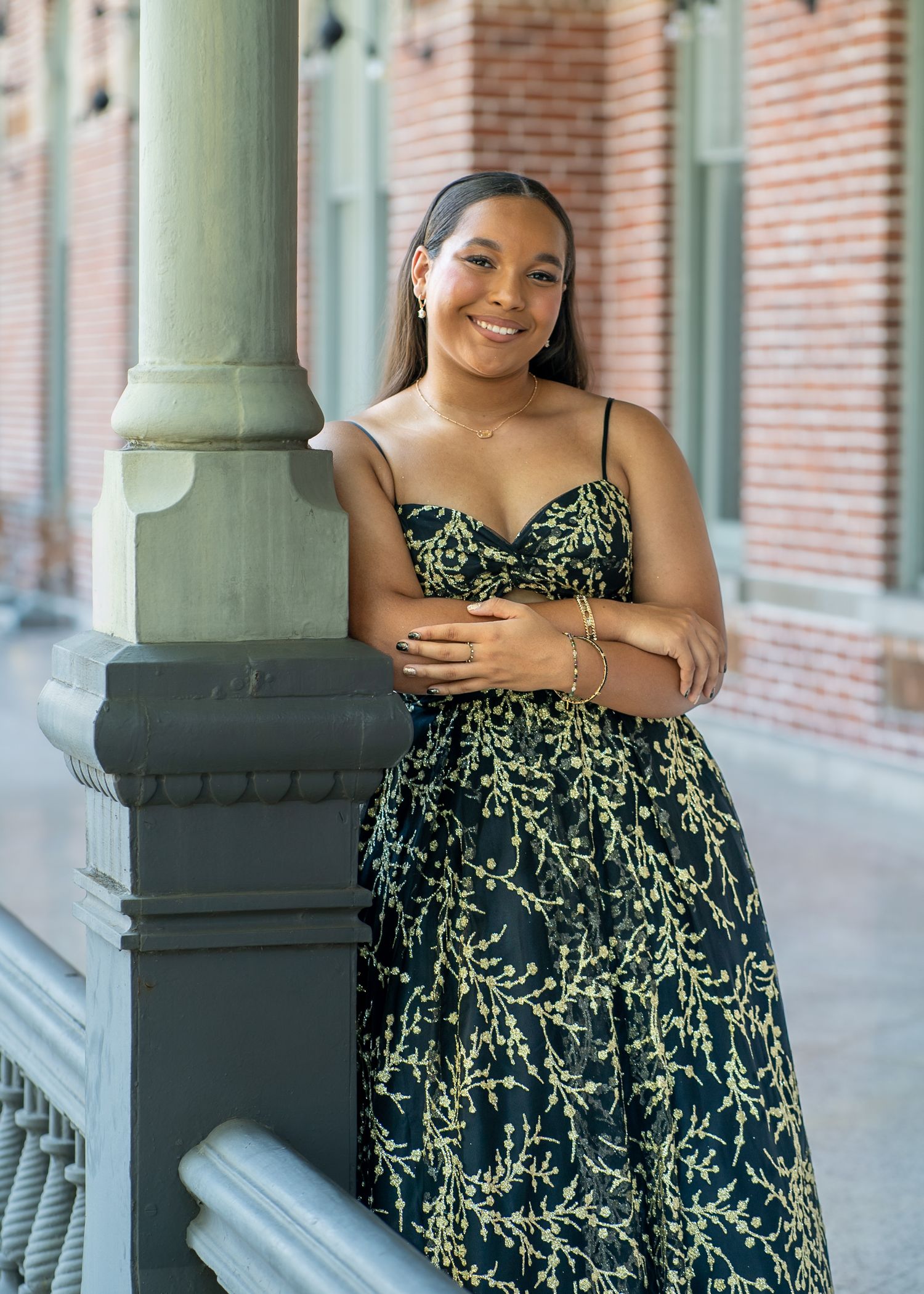 A person in a patterned dress poses elegantly against a classic architectural column.