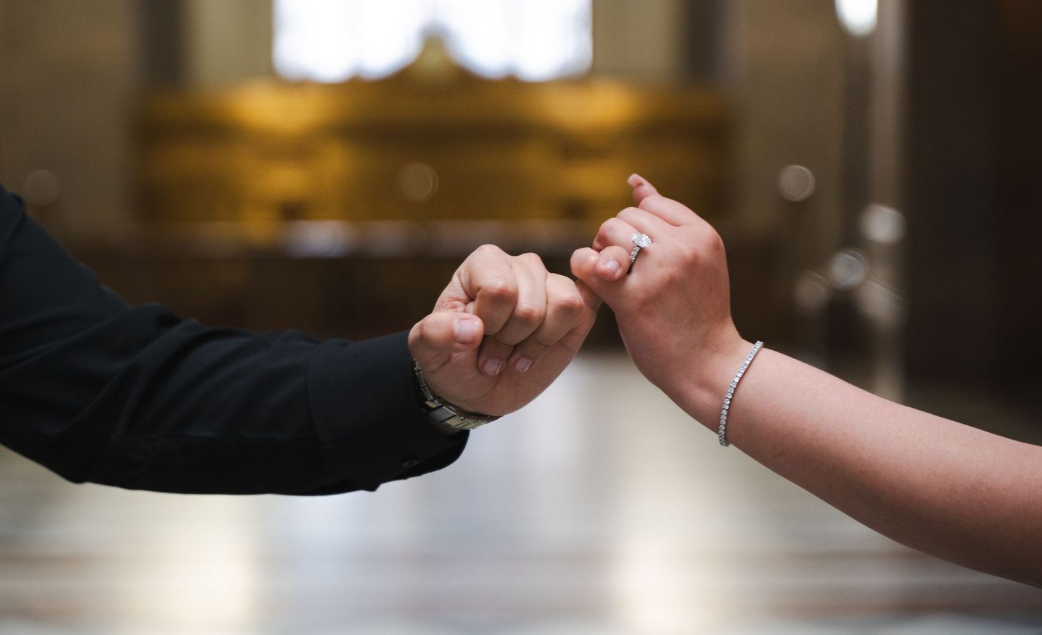 Couple holding hands in an intimate moment with warm lighting.