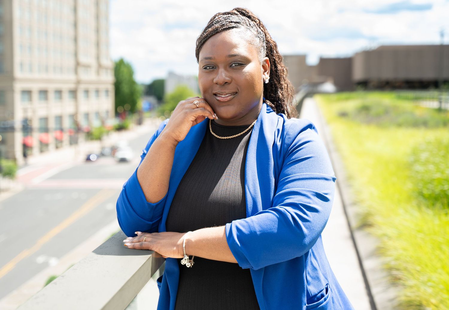 Casual portrait of person in blue blazer and black top against urban background.