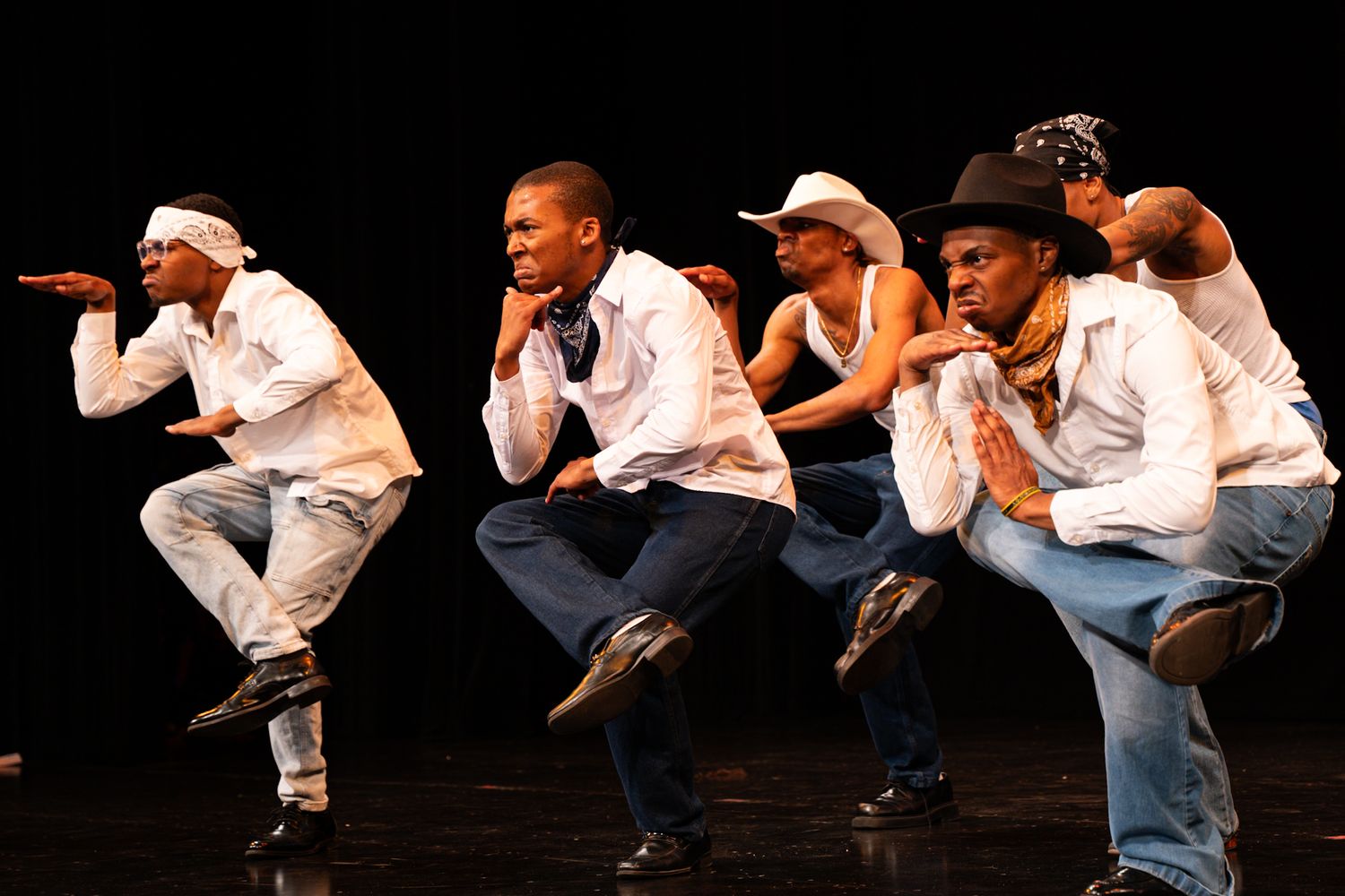 A sequence of dance moves showing a person in white and denim performing a crouching motion on stage.