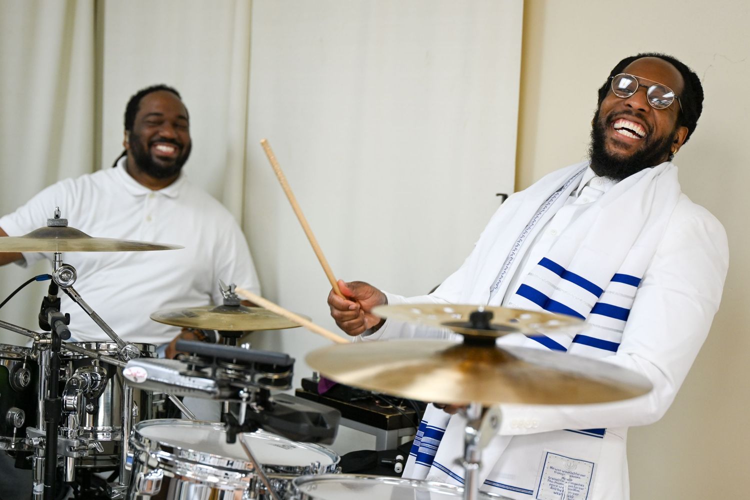 A musician in white plays drums with multiple shots showing different angles and expressions during the performance.