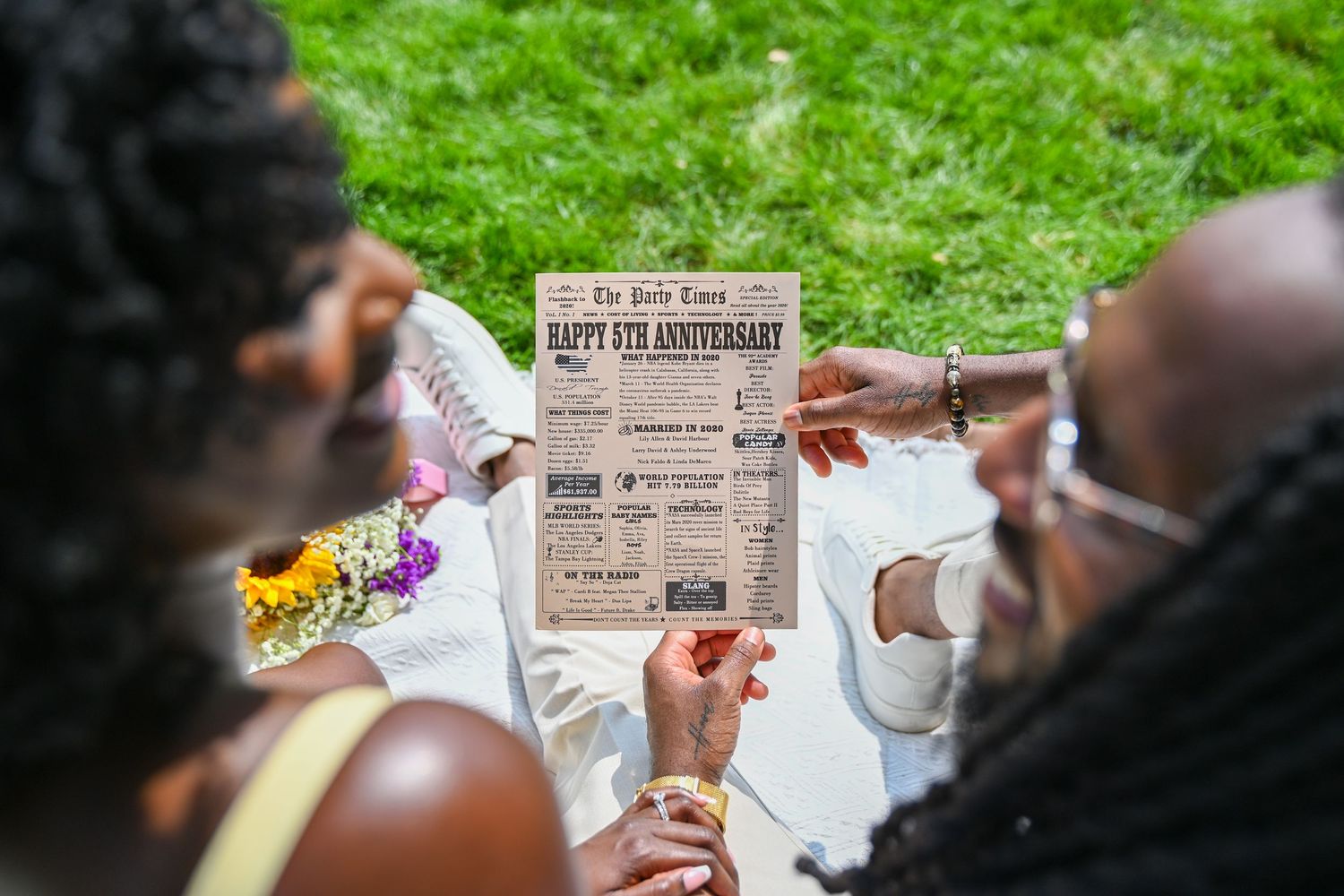 People enjoying an outdoor picnic while reading newspapers on grass.