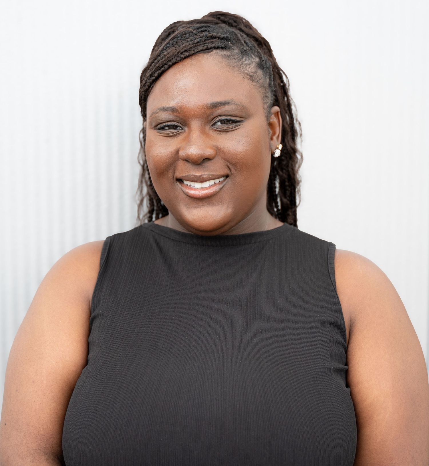 Professional headshot of person in black sleeveless top against white background.