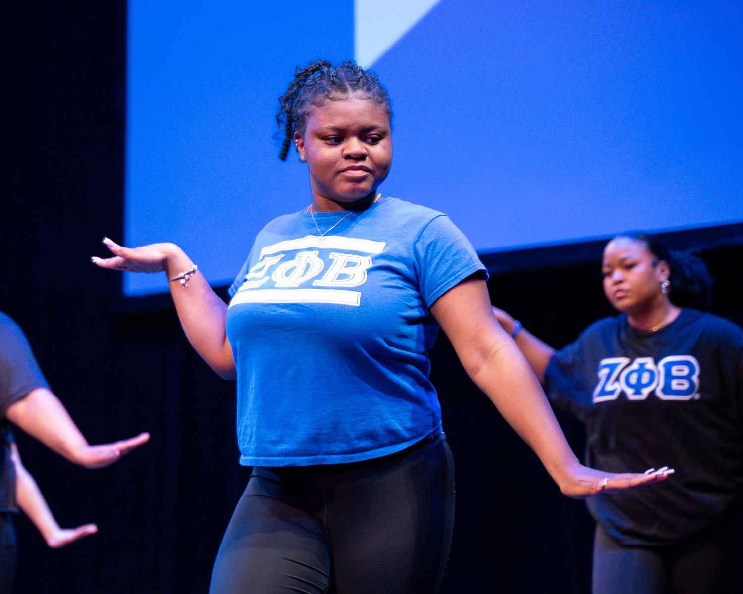 A group of dancers in blue and black outfits performing a synchronized dance routine on stage.