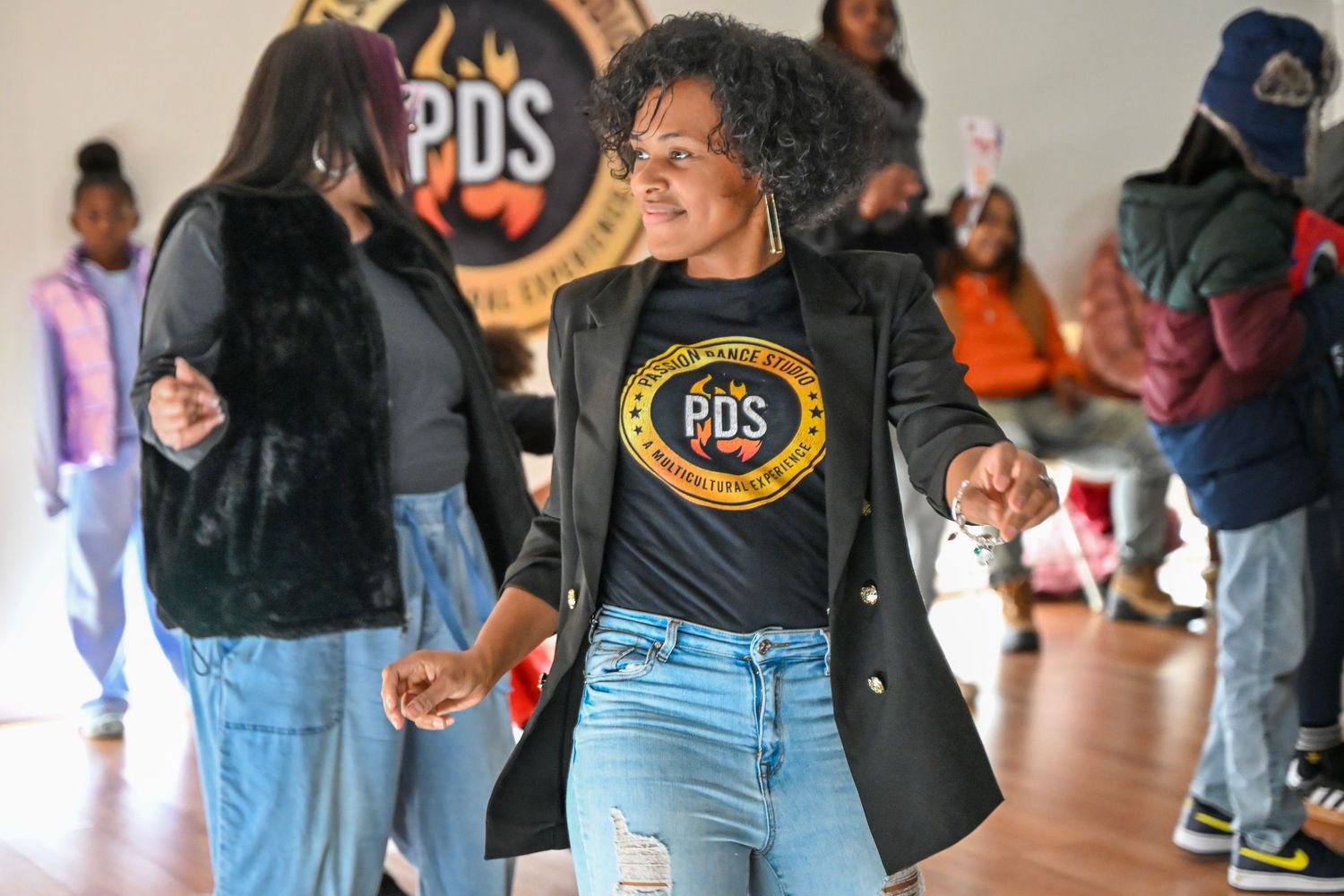 Group of dancers rehearsing moves in a spacious studio with hardwood floors.