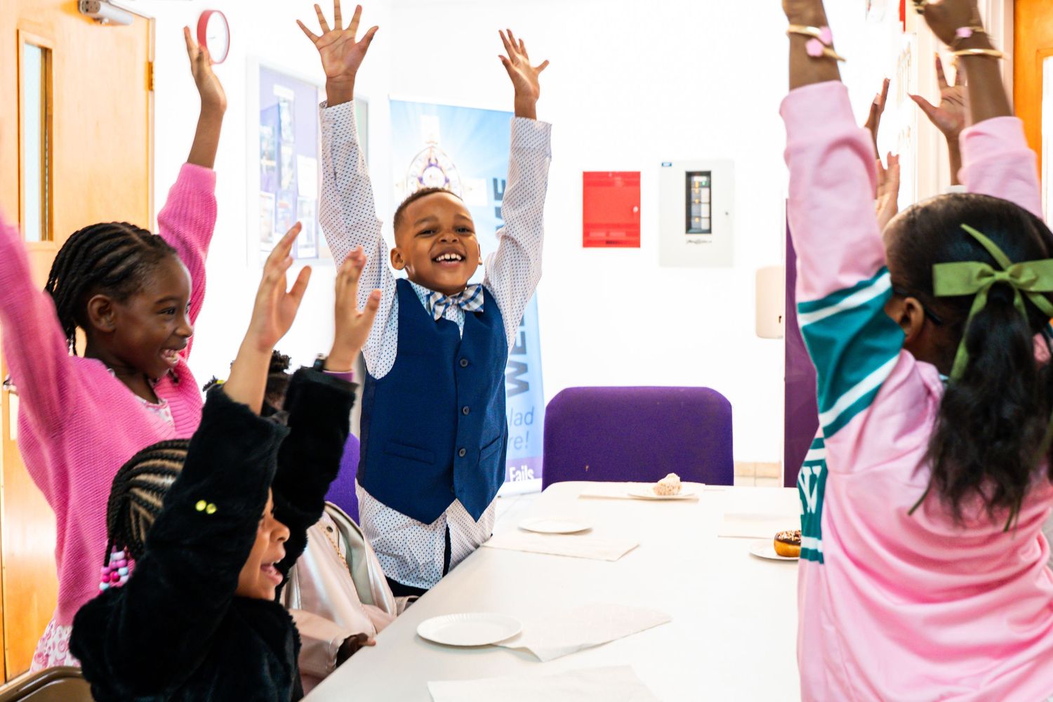 Students raising hands enthusiastically during an interactive classroom activity.