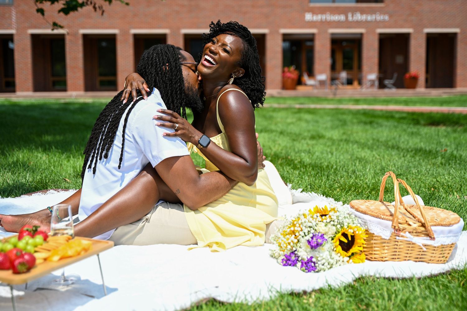 Couple having a romantic picnic on a blanket spread on green lawn.