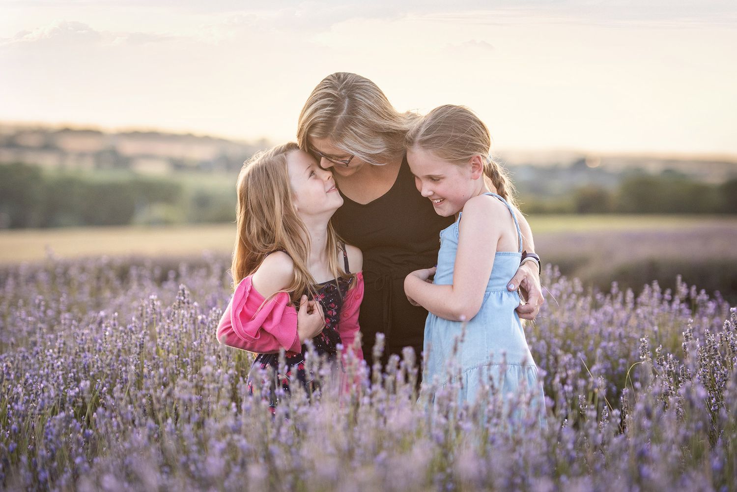 Two people and a young child explore a blooming lavender field during golden hour in the countryside.
