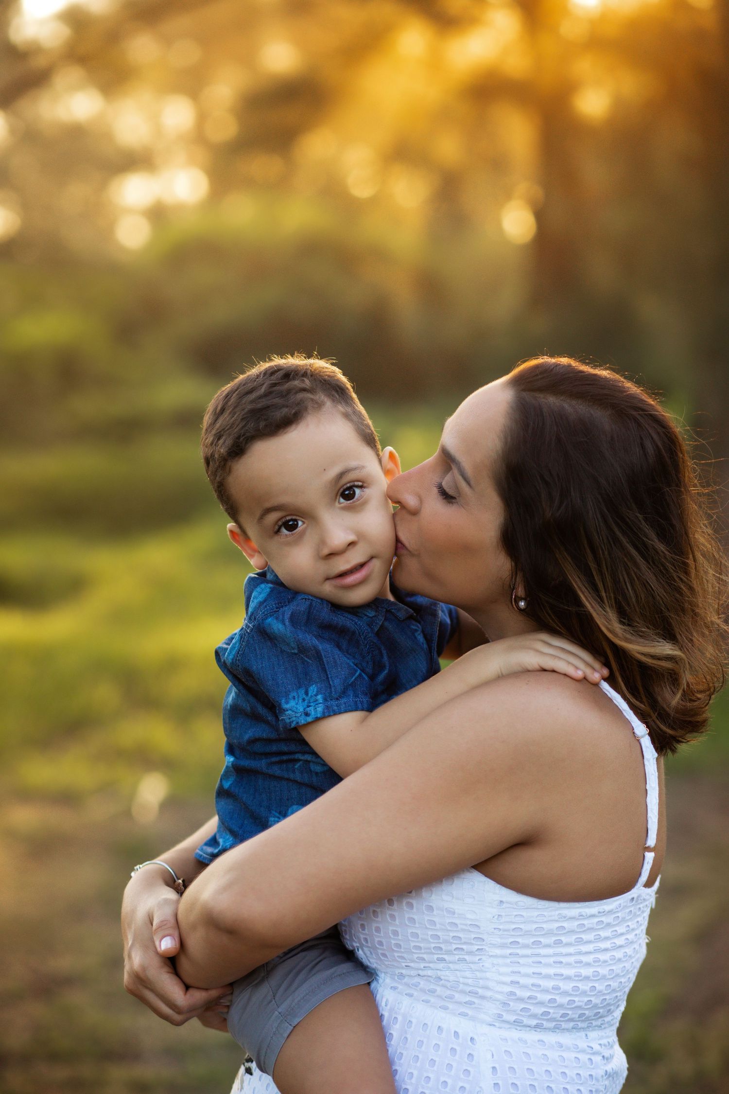 A tender moment between parent and child in golden sunlight with warm bokeh background.
