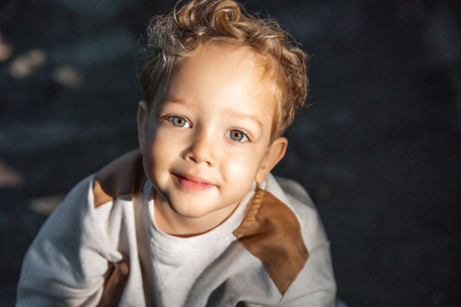 Close up portrait of young child with curly hair wearing white shirt.
