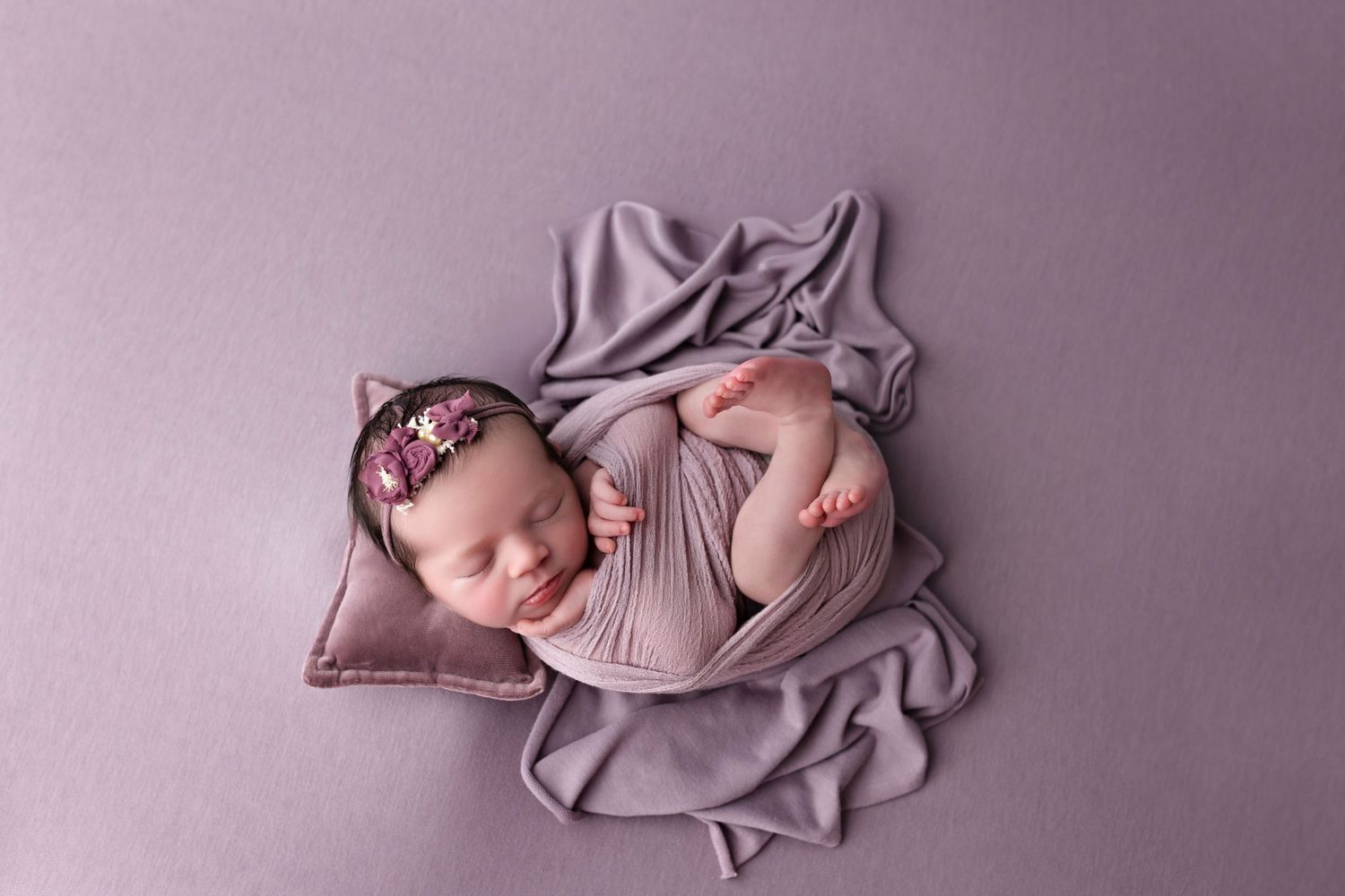 A collage of newborn photography poses on pink and mauve backdrops showing delicate sleeping positions and wraps.