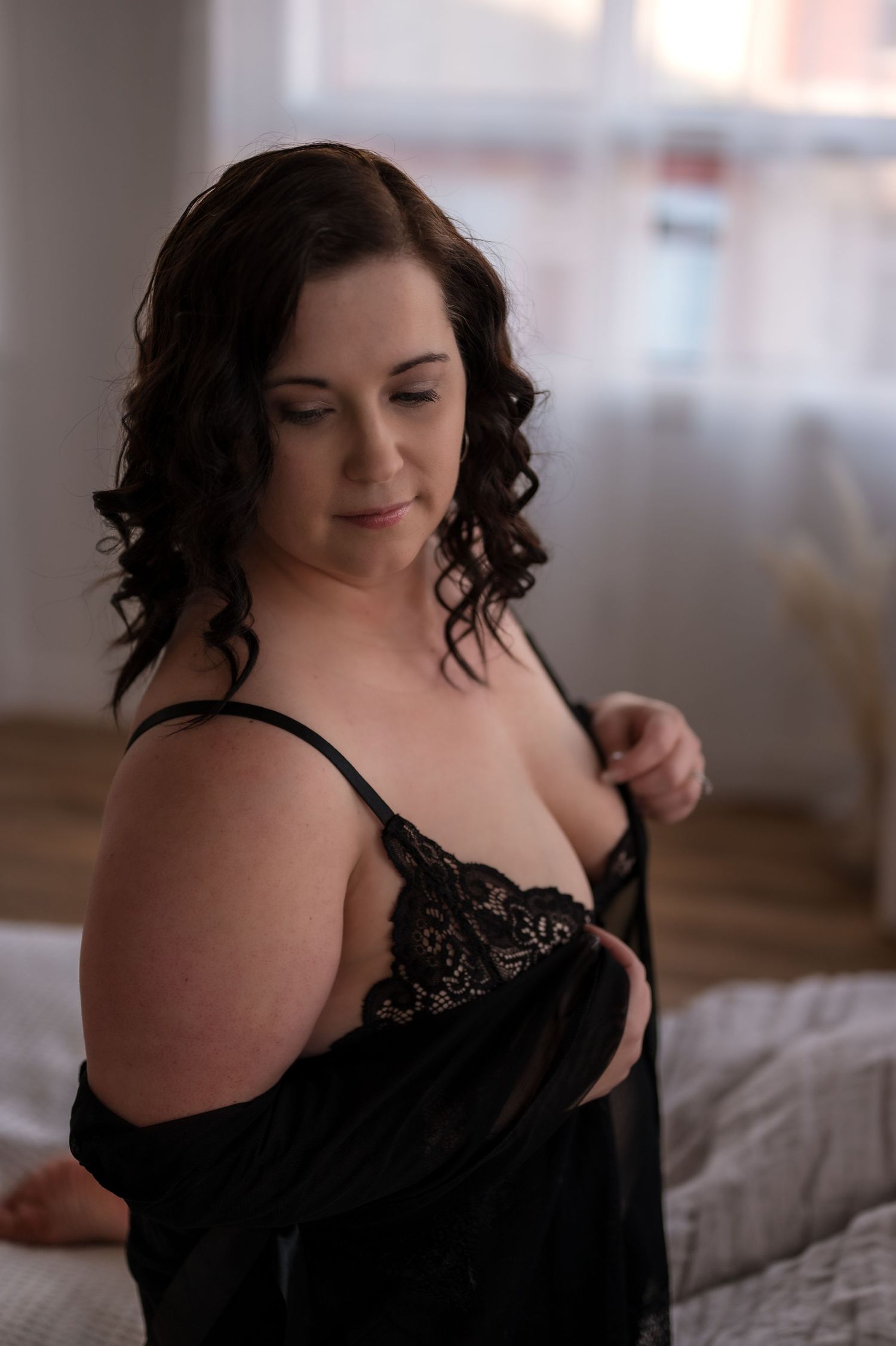 Boudoir session featuring romantic lighting and black lace lingerie on a cozy bed.
