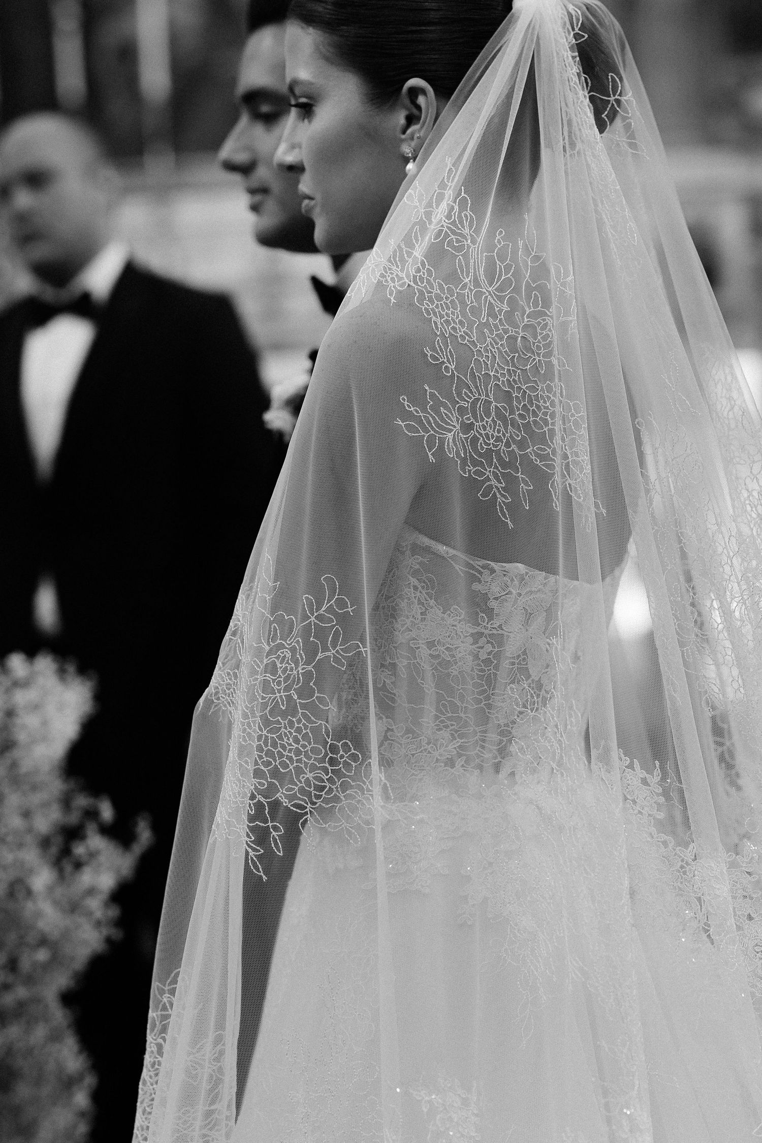 Beautiful wedding veil with delicate lace embroidery details shown in elegant black and white photography.