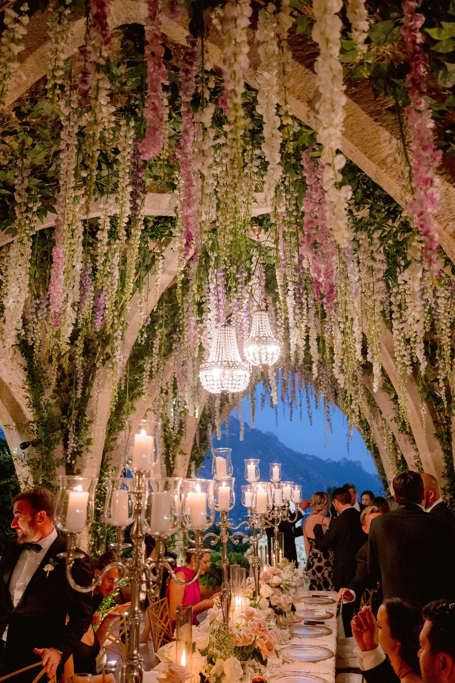 Elegant crypt of Villa Cimbrone setup with cascading floral installations and crystal chandeliers under a romantic evening sky.