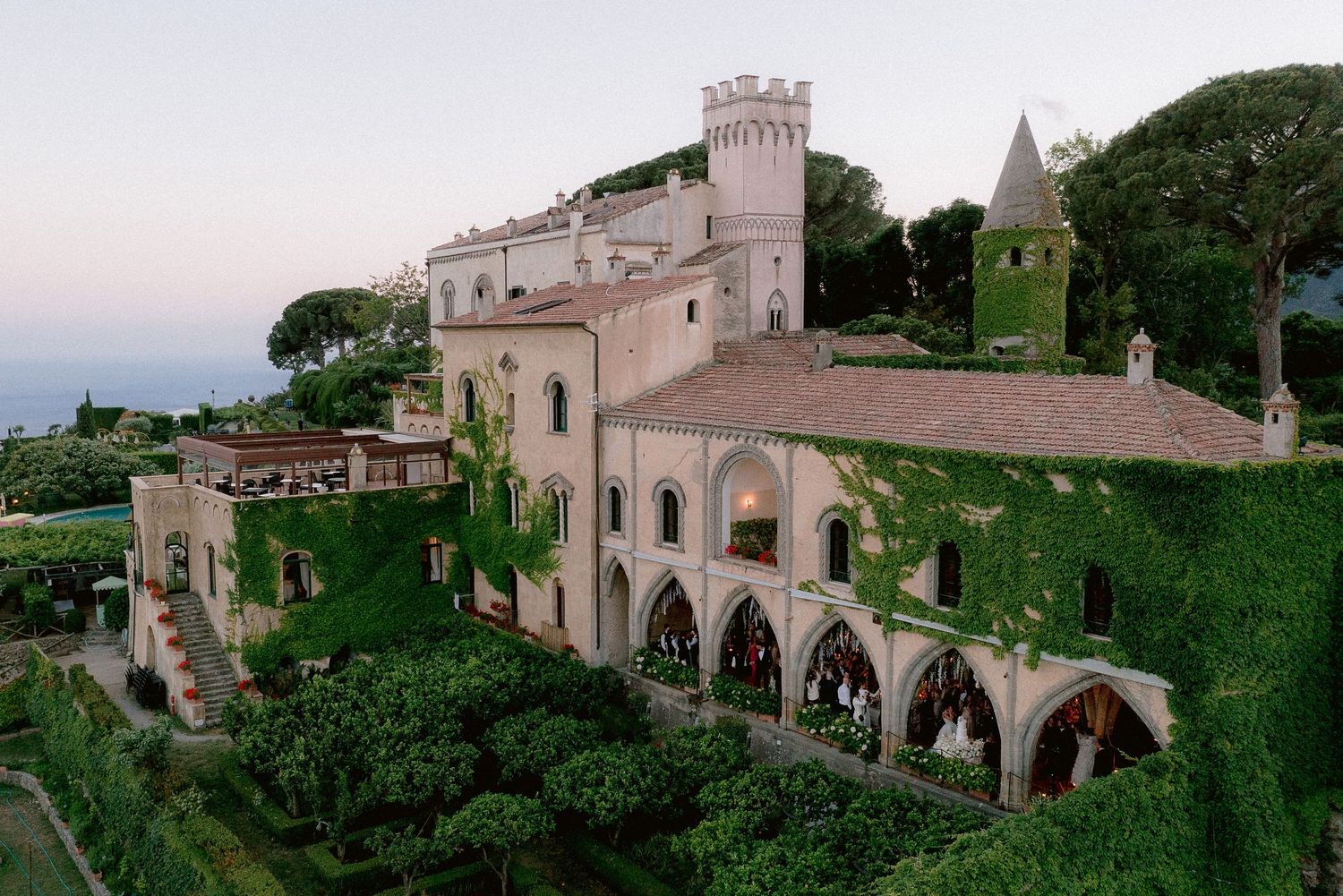 Historic crypt of Villa Cimbrone with ivy-covered stone arches and towers overlooking the sea at dusk in Ravello, Italy.