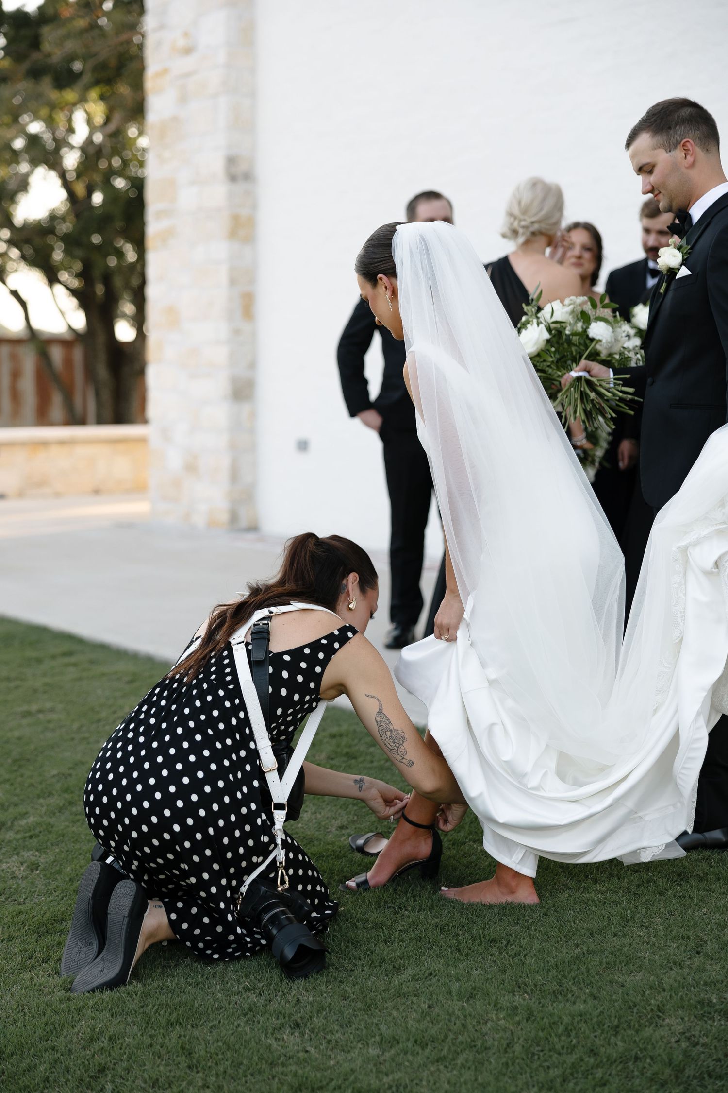 A series of wedding photos showing a person in a polka dot dress helping adjust a flowing white wedding gown on grass.