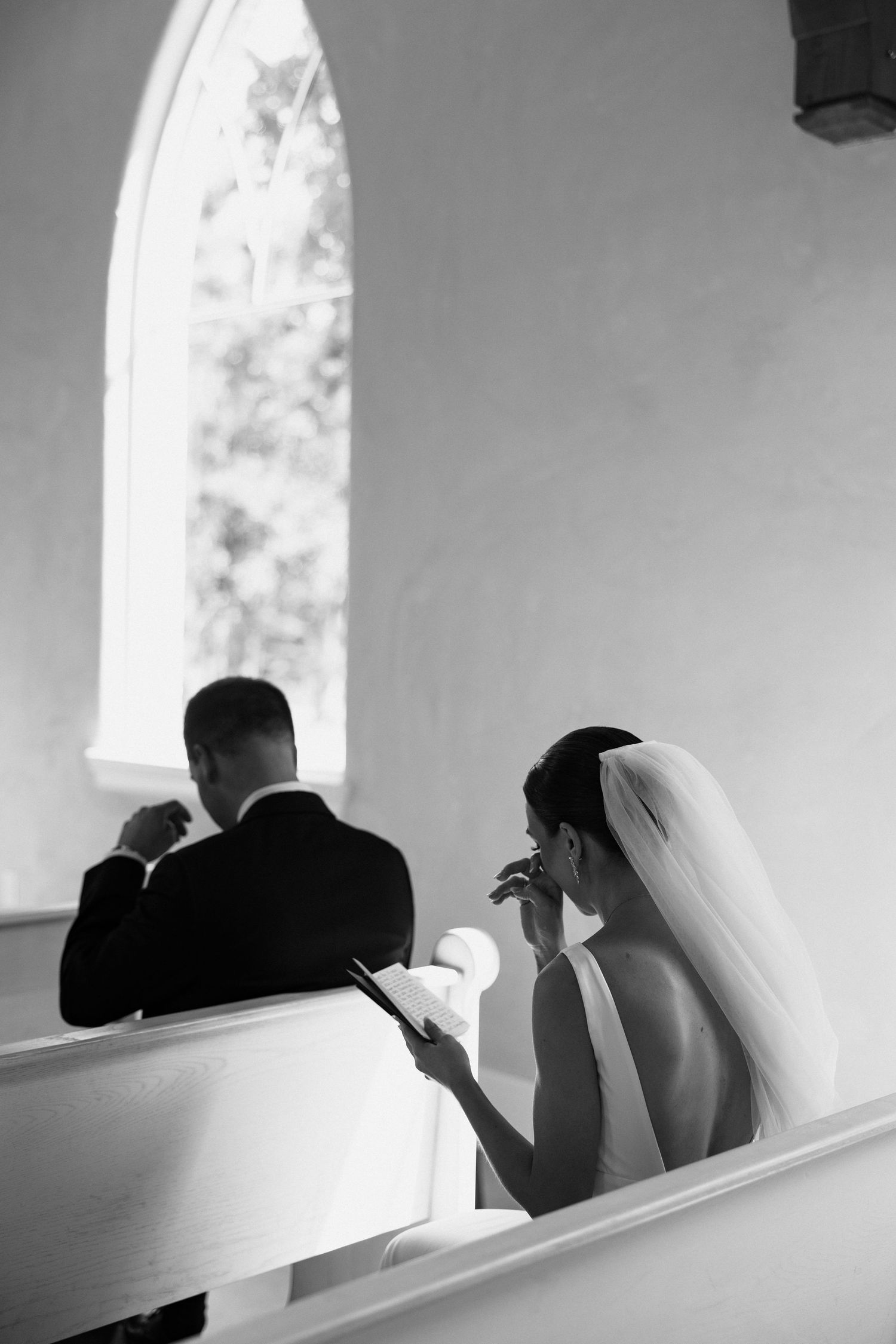 Black and white wedding photo sequence shows couple in church pews with dramatic window lighting.